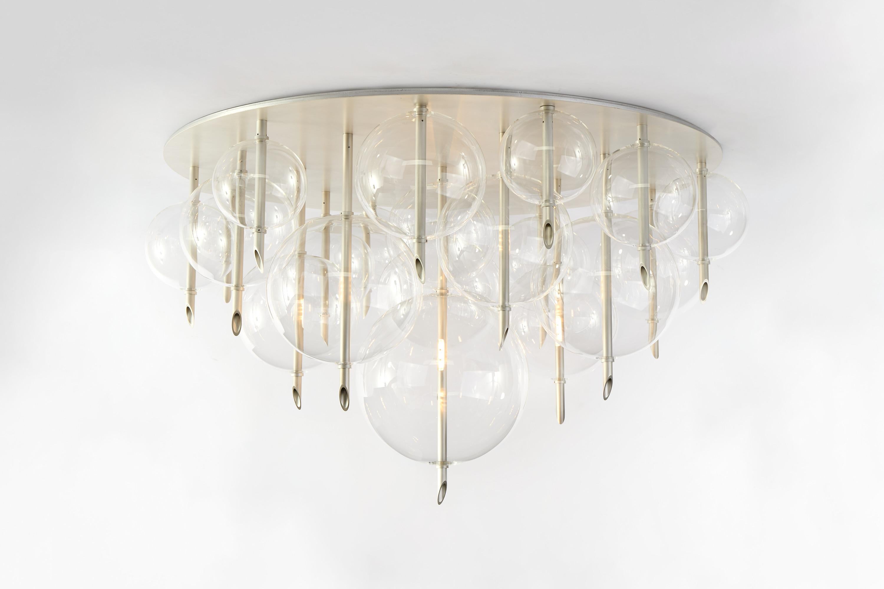Planetes S-19 is a sculptural flush-mount made of 19 hand-blown glass spheres — each one both different and unique, arranged close together to create a dense, sculptural composition that plays with transparency, layering, and luminous