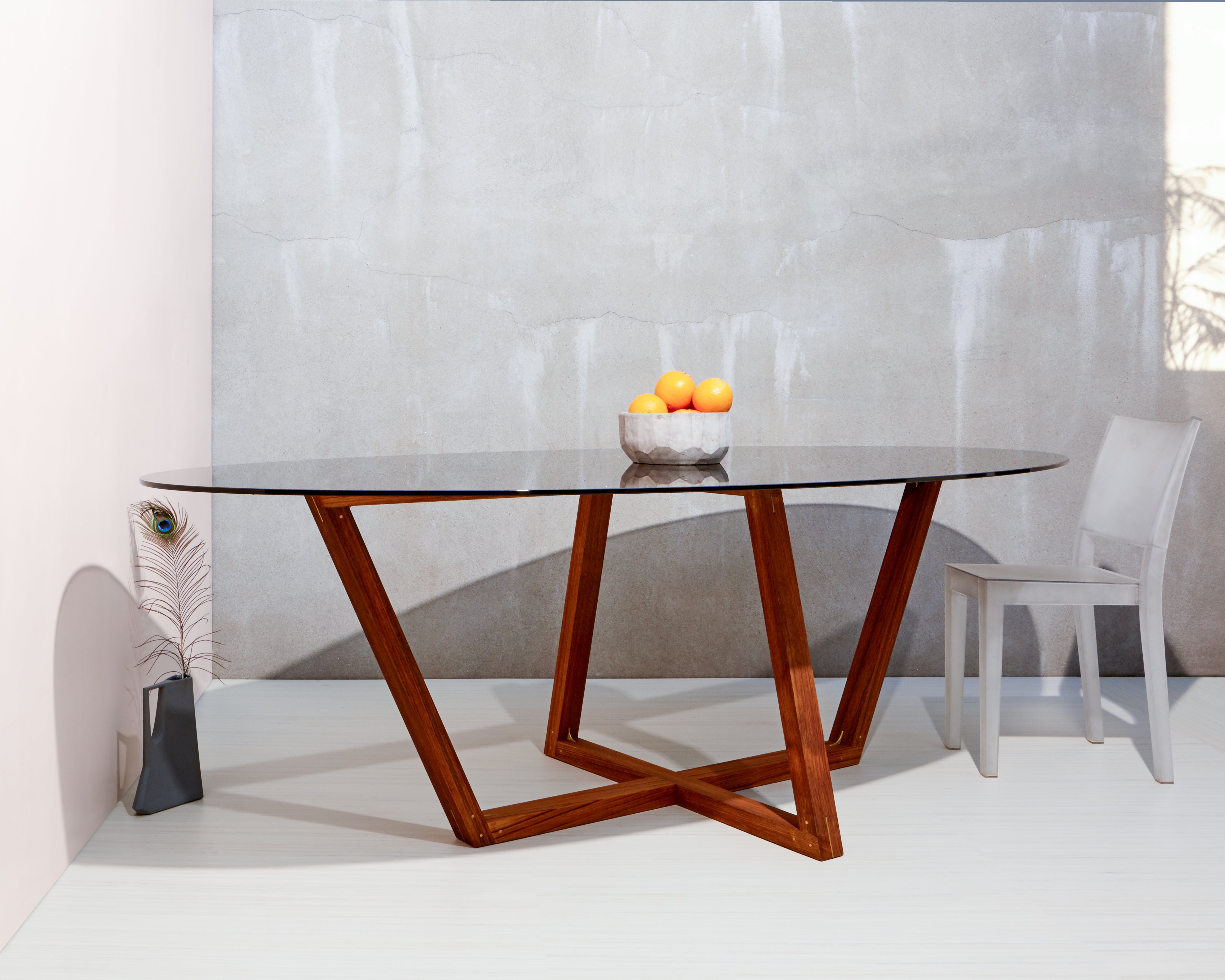 Trapezoidal forms of the finest teak interconnect in a dance of inverted symmetry beneath the smokey glass oval top.  Every view is different as you travel around the room creating a standout centerpiece for the astute collector looking for a bold