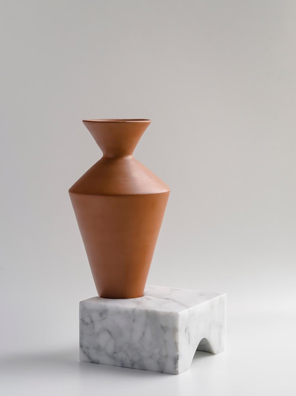 Die natürlichen Vasen aus Terrakotta, die in Elemente aus weißem Carrara eingearbeitet sind und sich im Gleichgewicht befinden, erzählen von Erfahrungen, vom Alltag, von Momenten; die Festigkeit der Basis verformt sich, um fragile Inhalte in ein