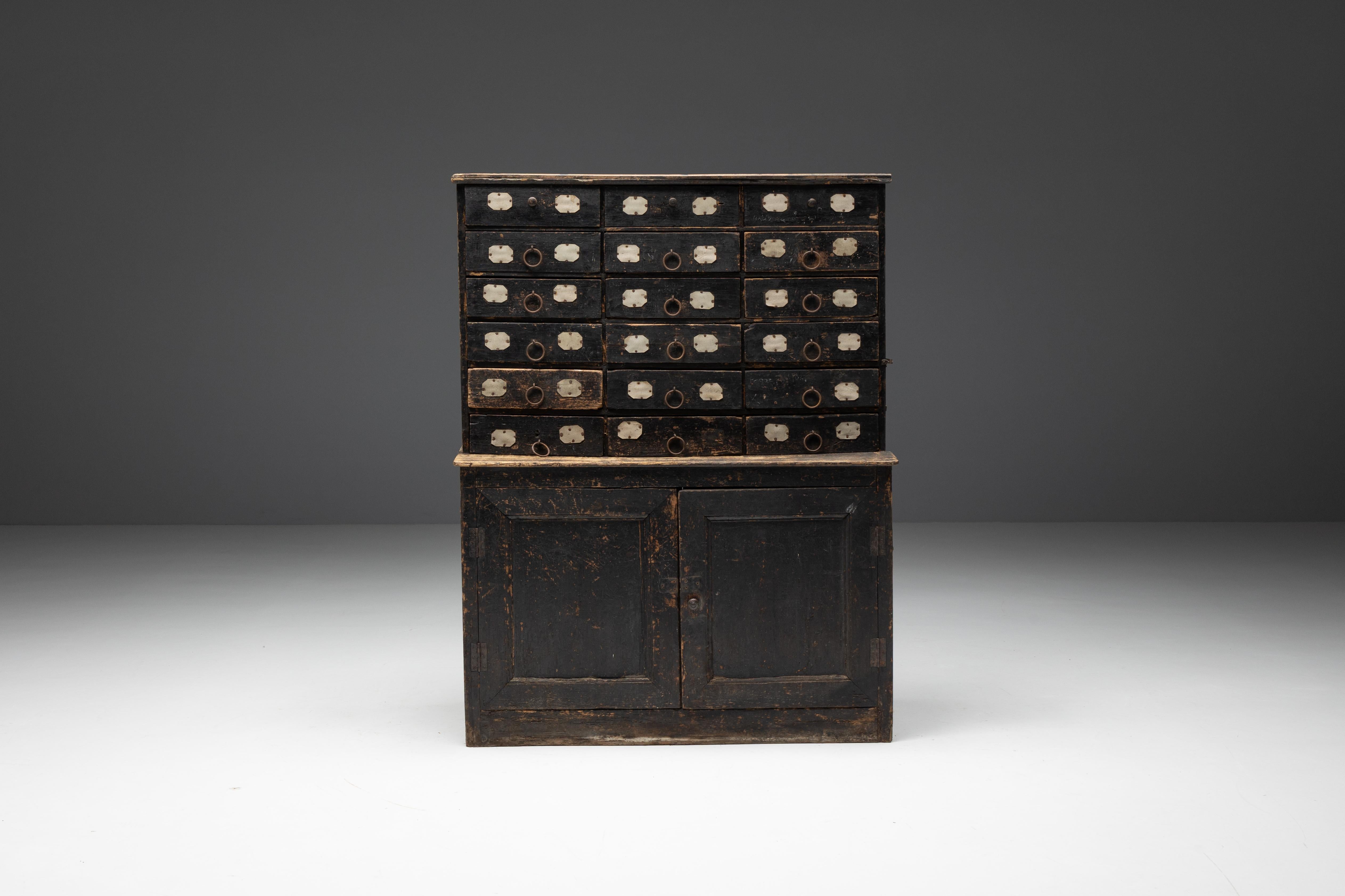 Rustikaler Apothekerschrank aus dunklem Holz aus dem Frankreich des 19. Jahrhunderts, der mit viel Liebe zum Detail gefertigt wurde. Im unteren Teil befindet sich ein geräumiger, geschlossener Schrank mit Einlegeböden, der viel Stauraum für Ihre