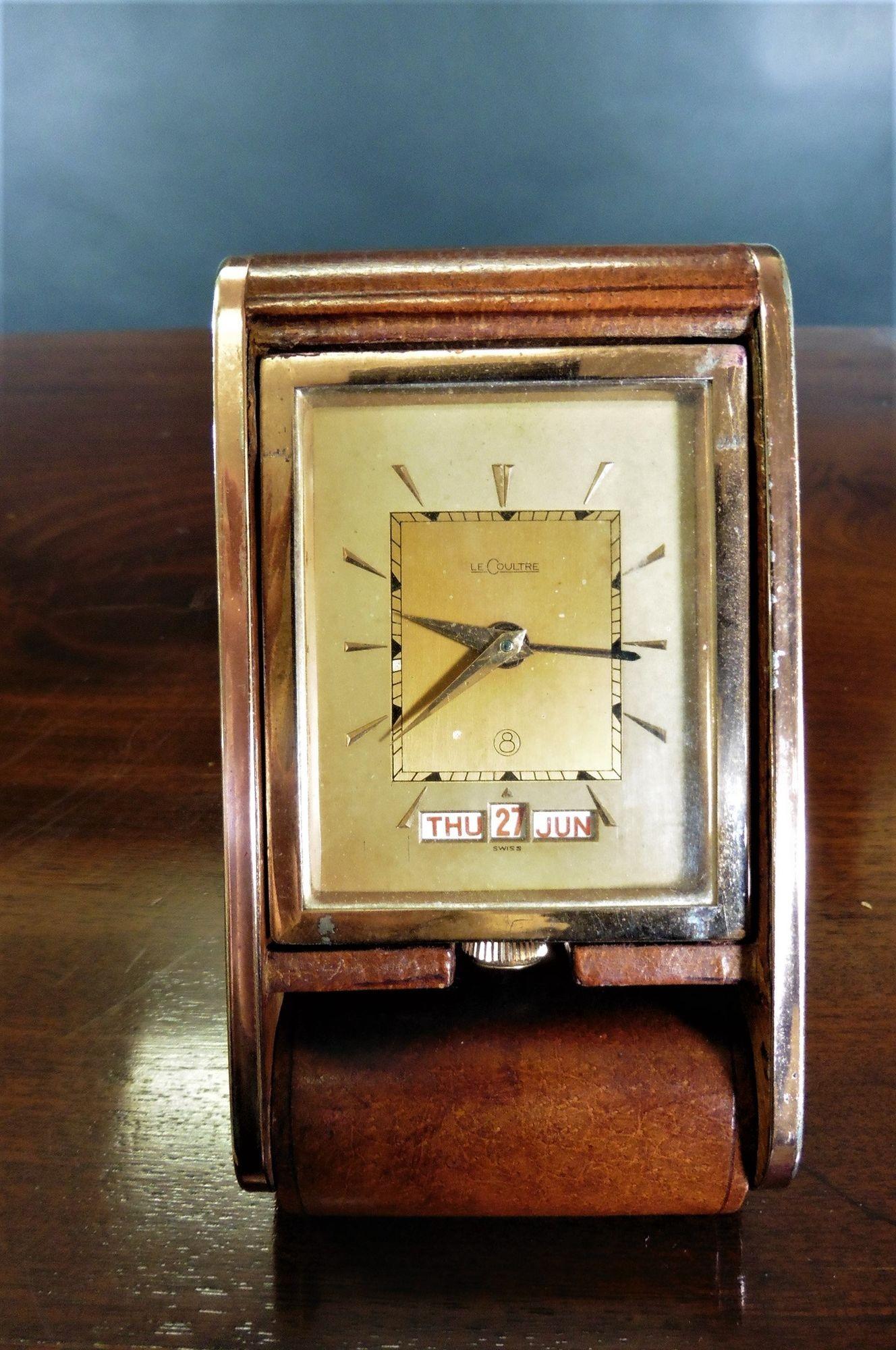 Travel alarm clock by Jaeger LeCoultre.
 
The case covered in fine brown leather, hinged to provide support and act as a cover when travelling. Copper sides and dial surround.
Gilded dial with original hands and calendar to the base signed Le