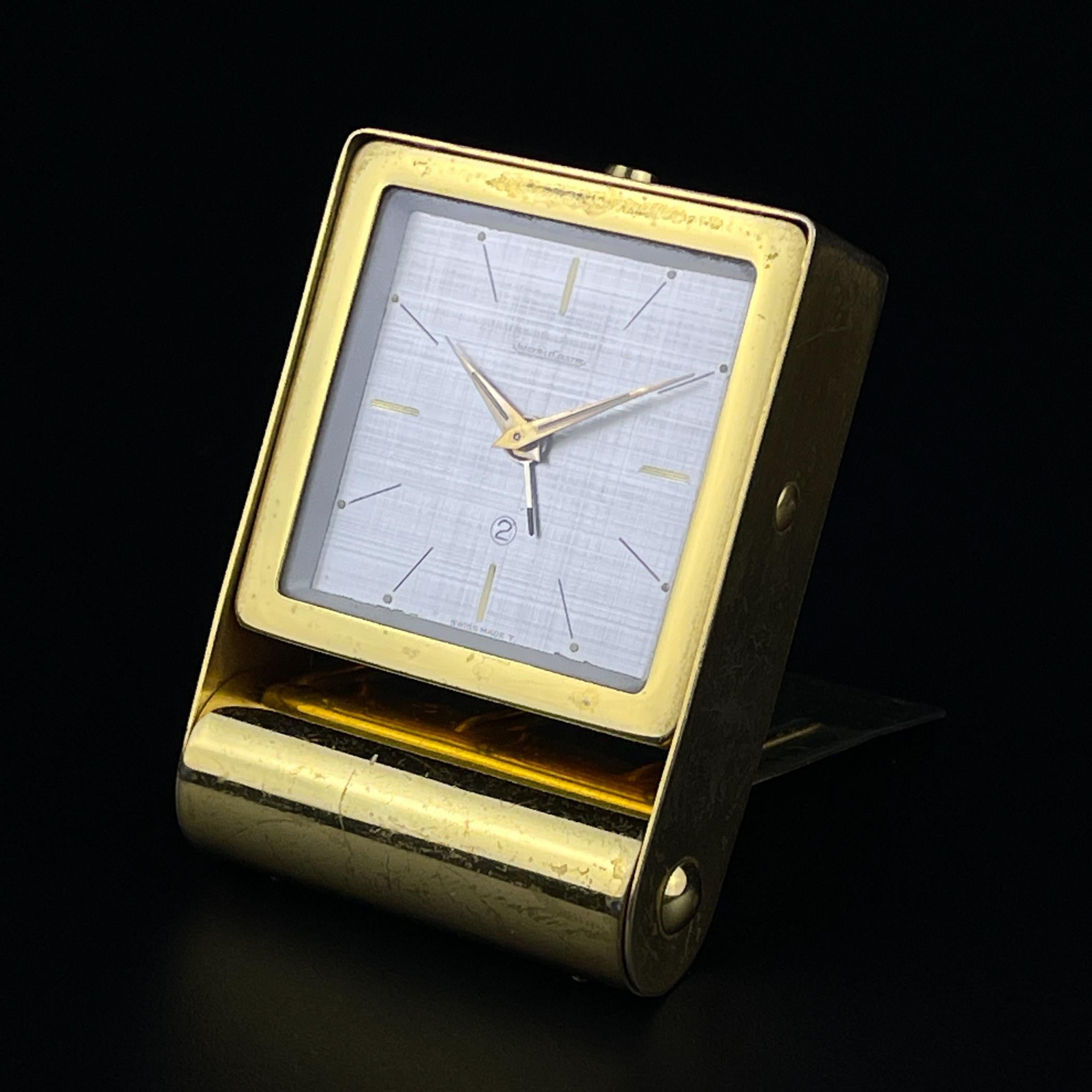 2-day travel alarm clock by famous Swiss watch factory Jaeger-LeCoultre made in Swiss in the 1950s.

Swiss manual winding movement. The lid folds down, allowing the alarm clock to be held open and upright.

Dimensions:
Width: 5.5 cm / 2.1
