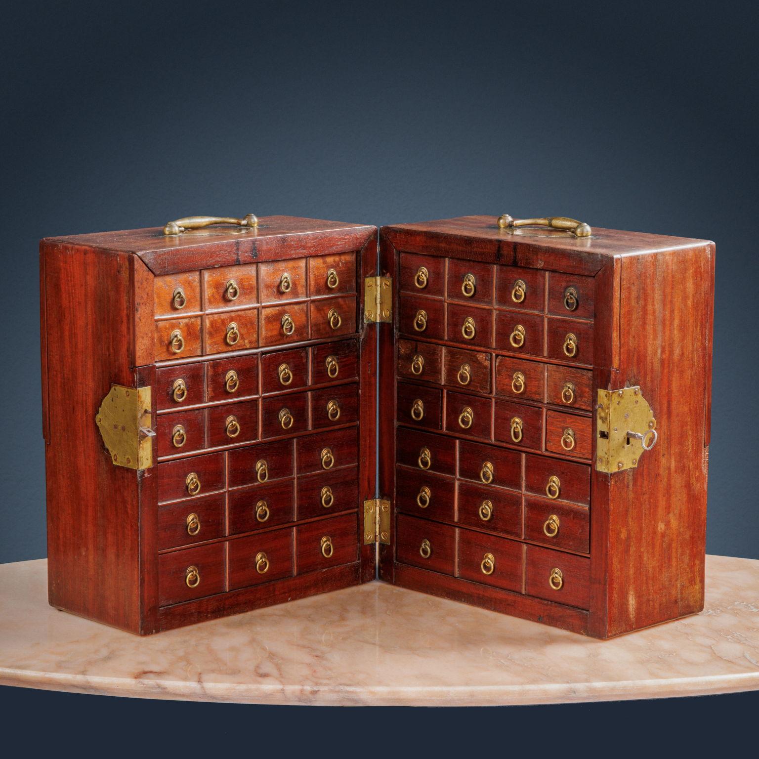 Spice box, commonly called “travel pharmacy”. Divided specularly in half, the piece of furniture closes with a central lock which also blocks the two side tables which conceal the glass bottles. Inside, the space is divided into small drawers, some,