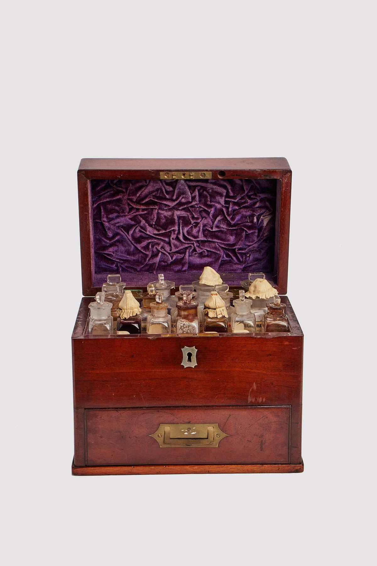 Travel pharmacy. Box in Mogano Sipo ( Entandrophragma utile ) wood and brass with recessed handles on both sides and a drawer on the front. The upper level opens, inside it there are a group of glass bottles (some with labels), arranged in