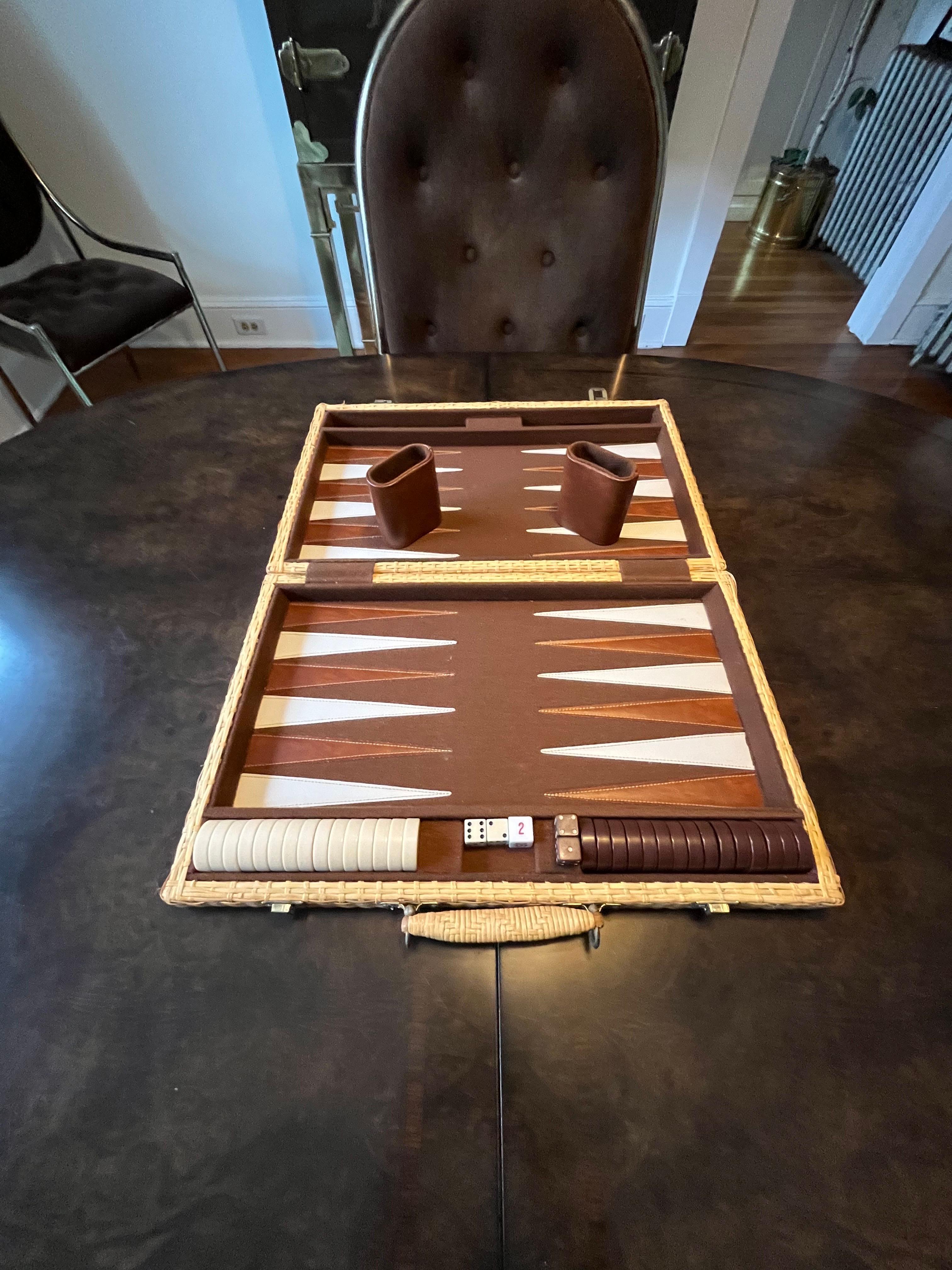 Beautiful wicker portable backgammon board. Brass hardware and wooden frame completely wrapped in wicker. Brown felt interior and brown and cream triangles for gameplay. Board includes all brown and cream chips, 2 brown and 2 white dice as well as a