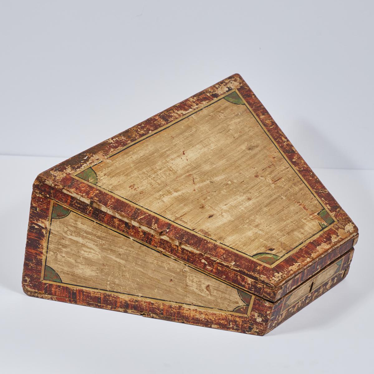 Traveling desk box from Georgian England. With Italiante metal carrying handle and lock, hand-painted faux bois siding and verdirgis demi-lune accents, the piece is handsome and whimsical at once. The trapezoidal shape makes for comfortable