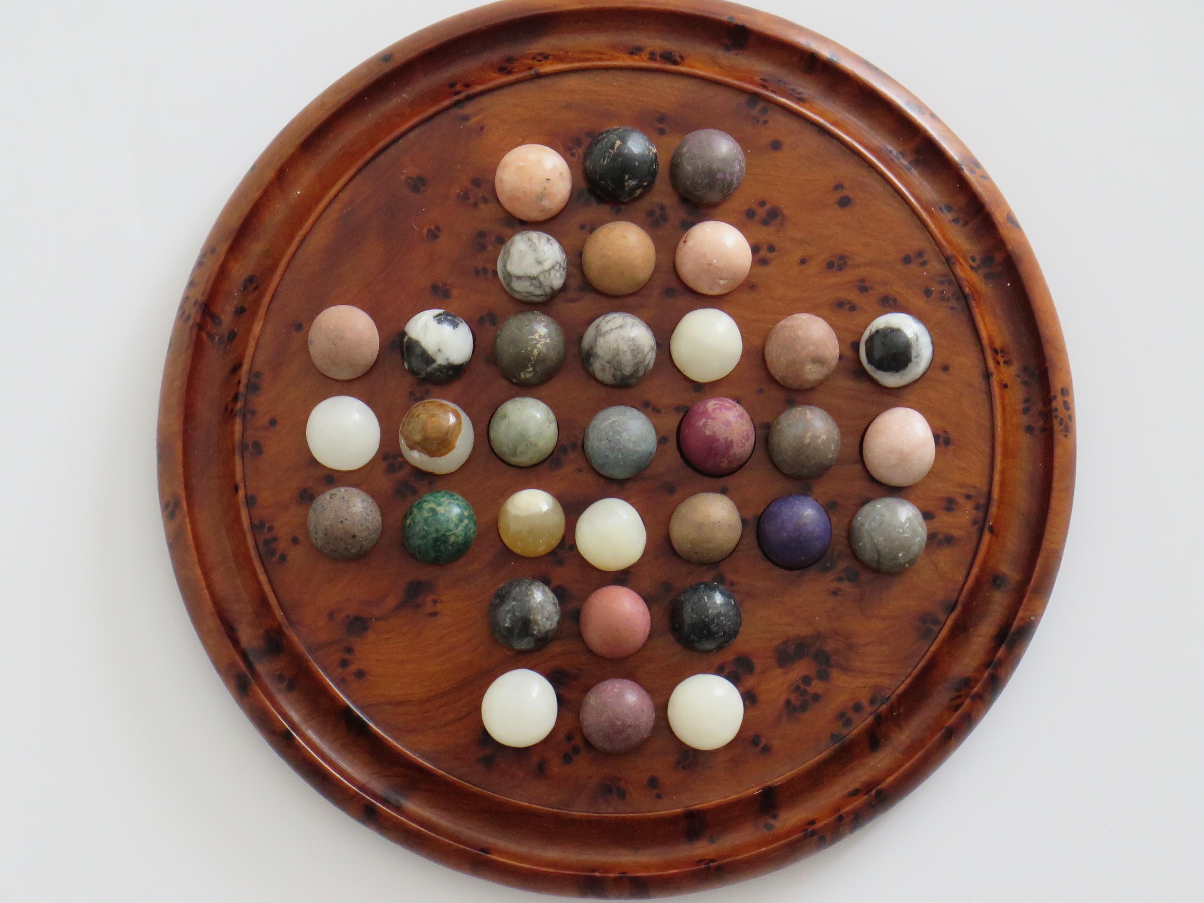 This is a very good and complete small board game of Travelling Marble Solitaire, which we date to the early 20th Century with most of the marbles being earlier, back to the 19th Century.

The circular turned board is very attractive being made of a