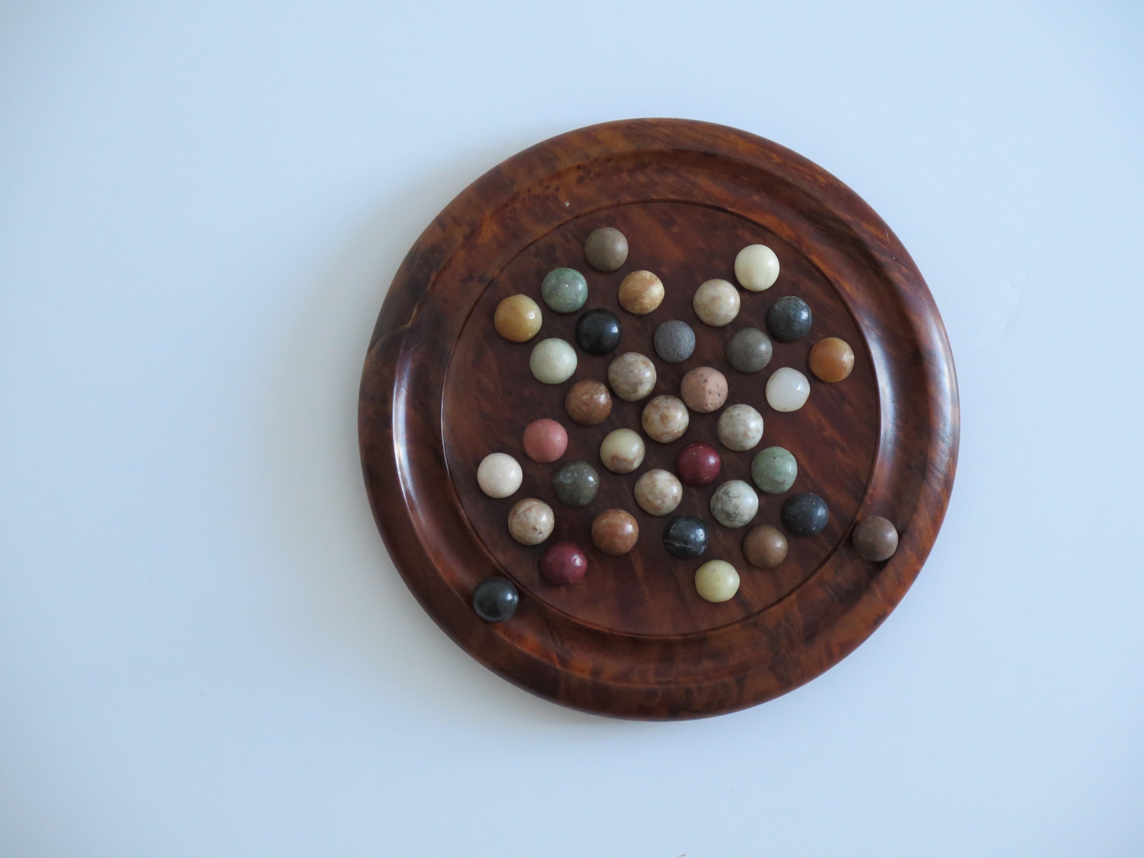 This is a very good and complete board game of Marble Solitaire, with a hand turned hardwood board and 35 agate stone and clay marbles, which we date to the late Art Deco period of the 20th Century, Circa 1930.

The circular turned board is very