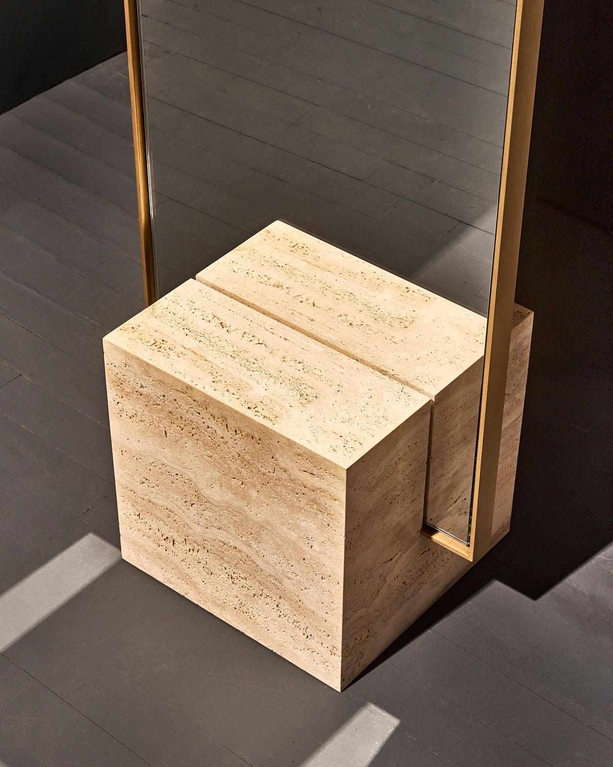 The coexist standing mirror consists of a honed travertine cube base, brushed brass mirror frame, and finished backing. The mirror can stand alone or be set near a wall. 

The brass framed mirror fits into a rich stone cube base with precision. The