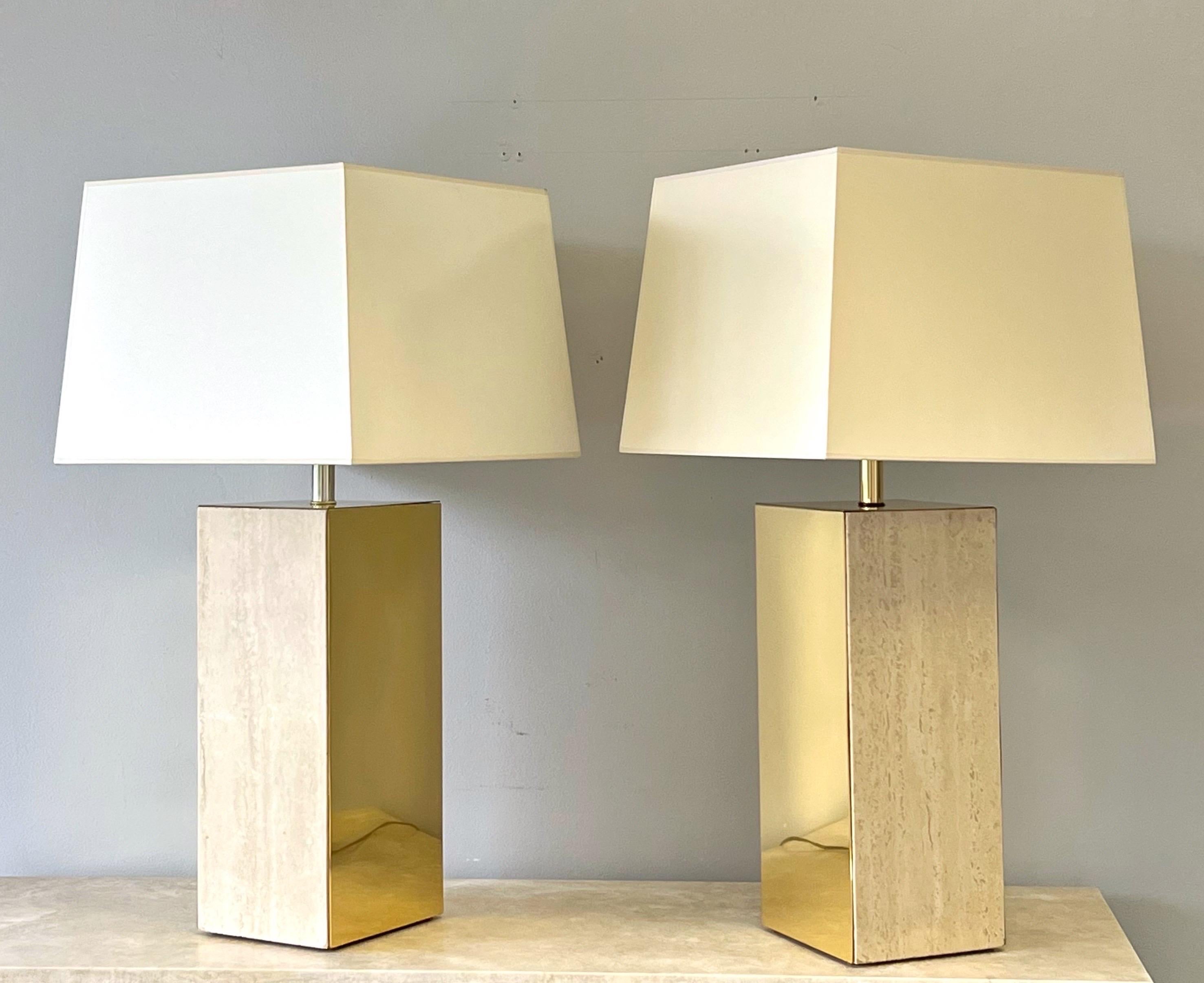 A pair of large brass and travertine table lamps. The bases are 7” by 8” by 18” tall. Very clean modern lines and proportions. 