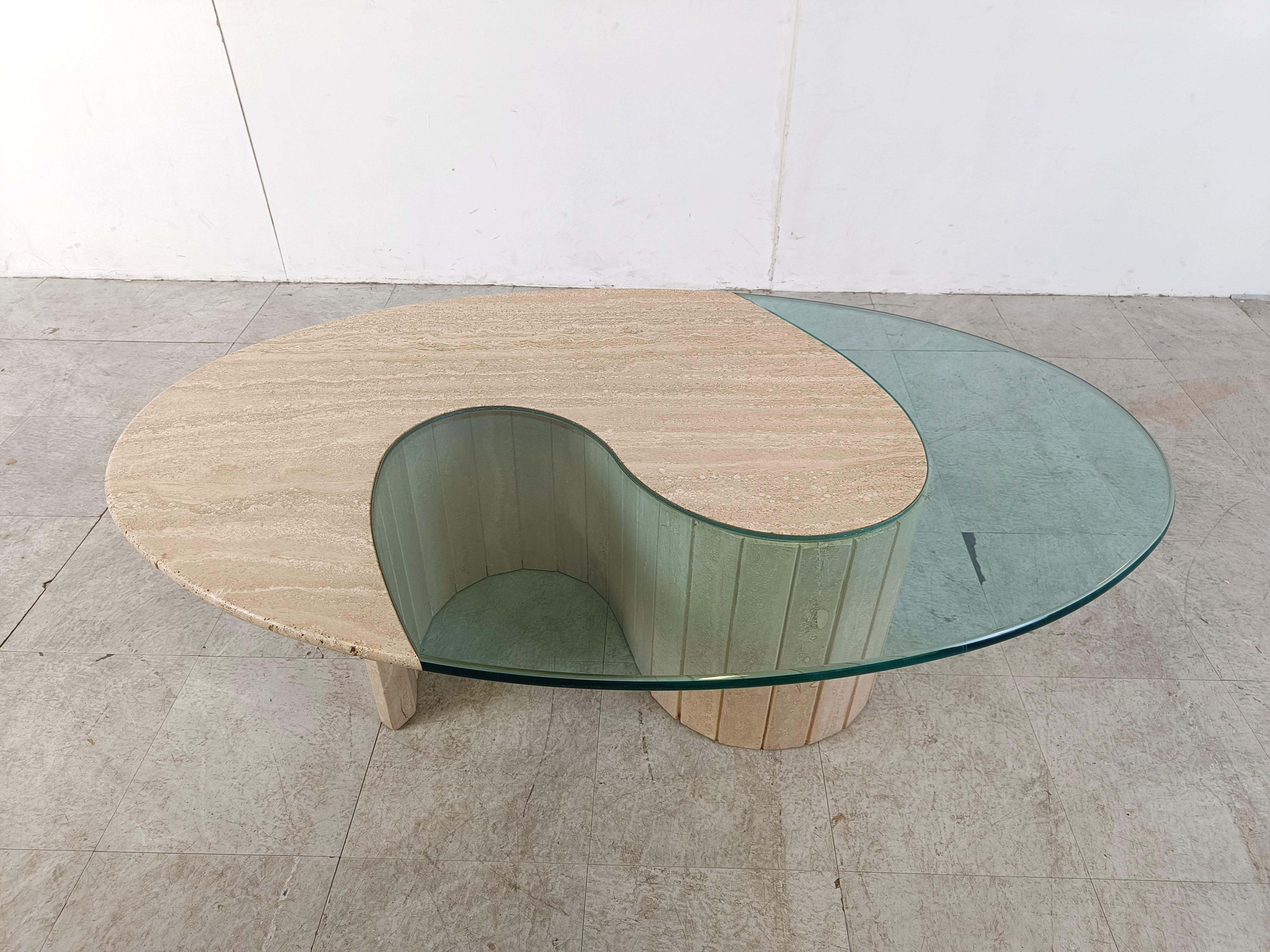 Unique oval travertine and glass coffee table.

The table top consists of a ying & yang shaped top with integrated glass mounted on a reeded travertine base

1970s - Italy

Height: 40cm/15.74