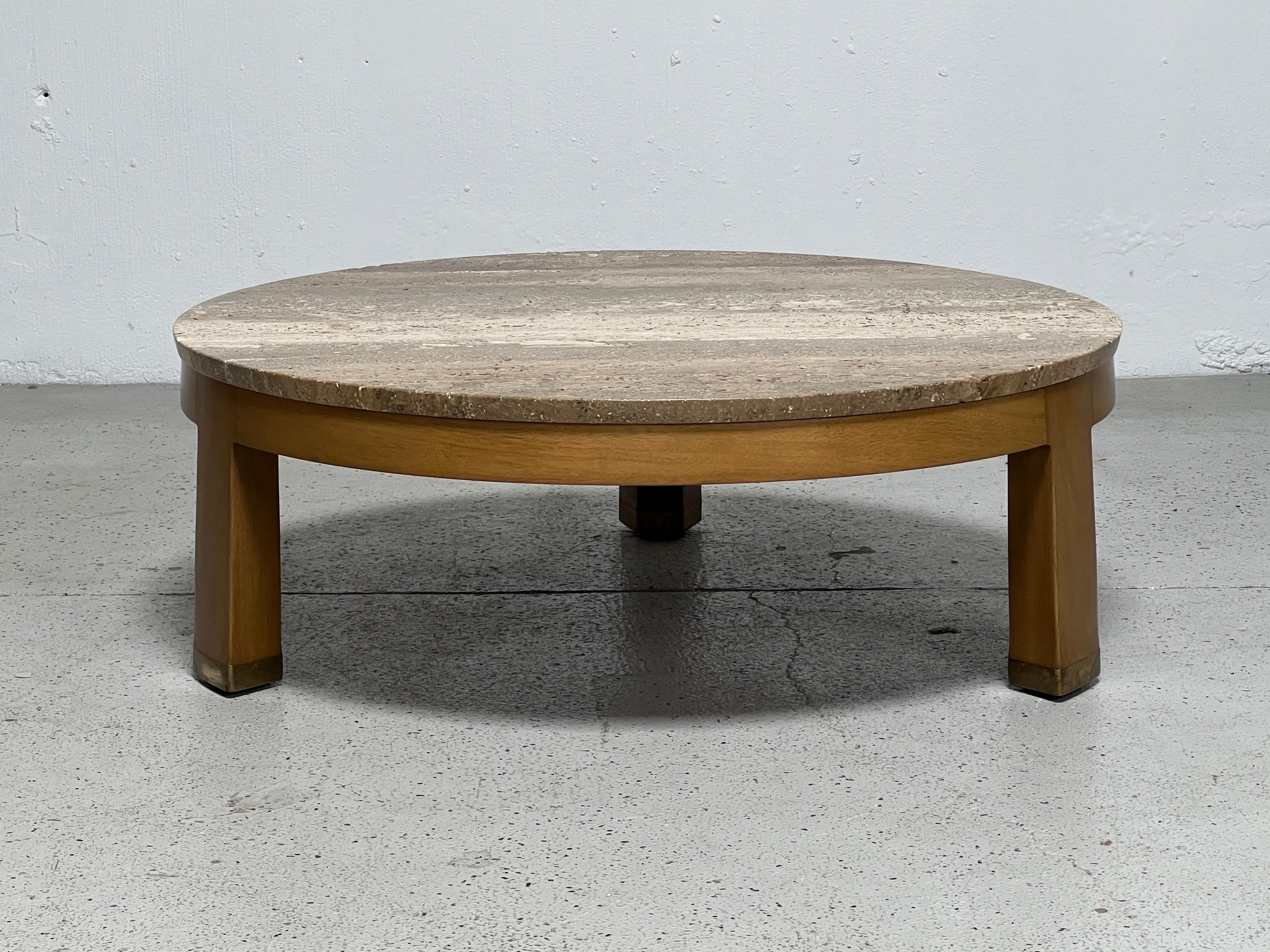 A low coffee table with three legged mahogany base, brass feet and travertine top. Designed by Edward Wormley for Dunbar. 