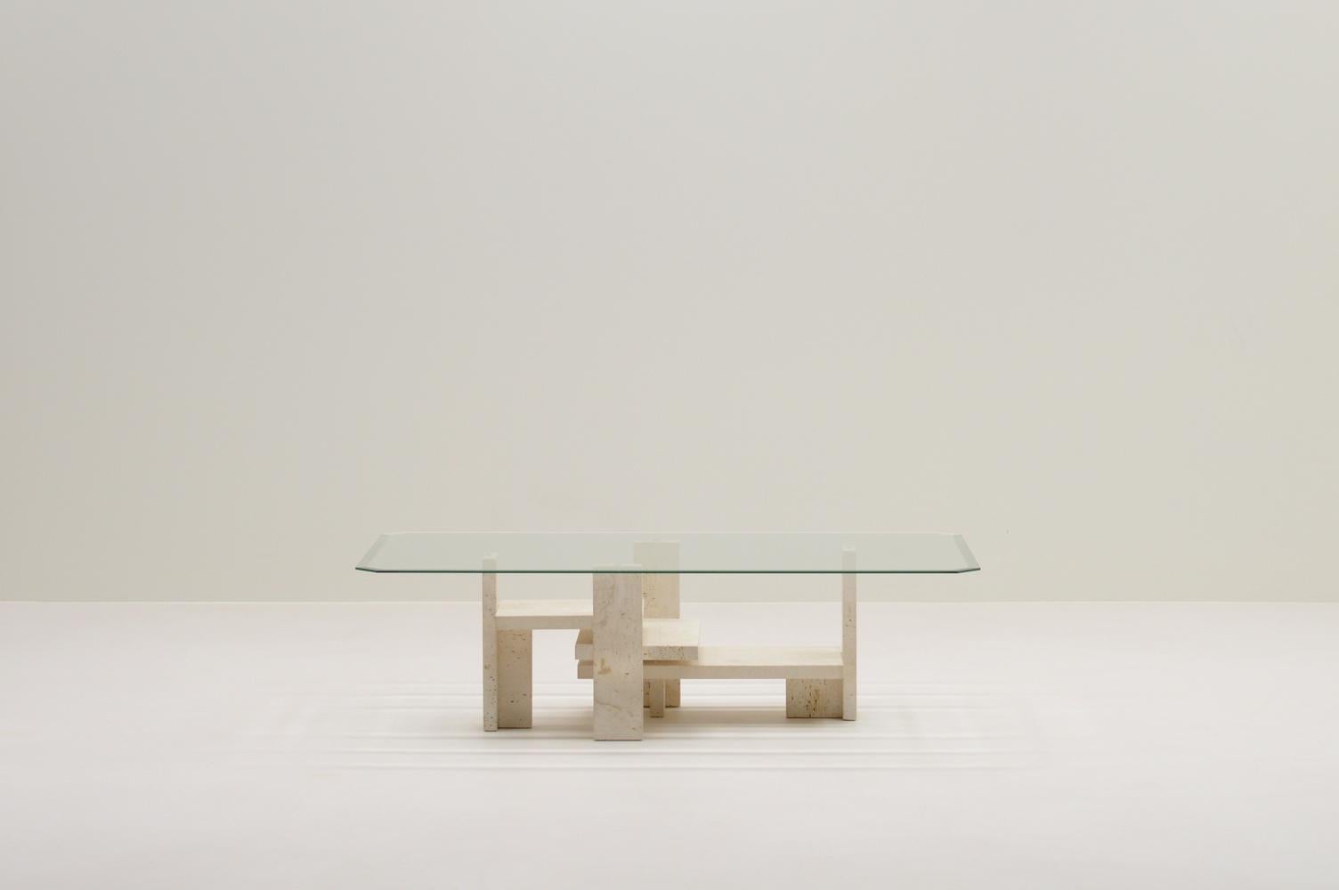 Travertine coffee table by Willy Ballez, 1970s Belgium. This sculptural coffee table was manufactured in his own atelier in Belgium. Multiple slabs of solid travertine make a beautiful base. Still with its original glass beveled top. The coffee