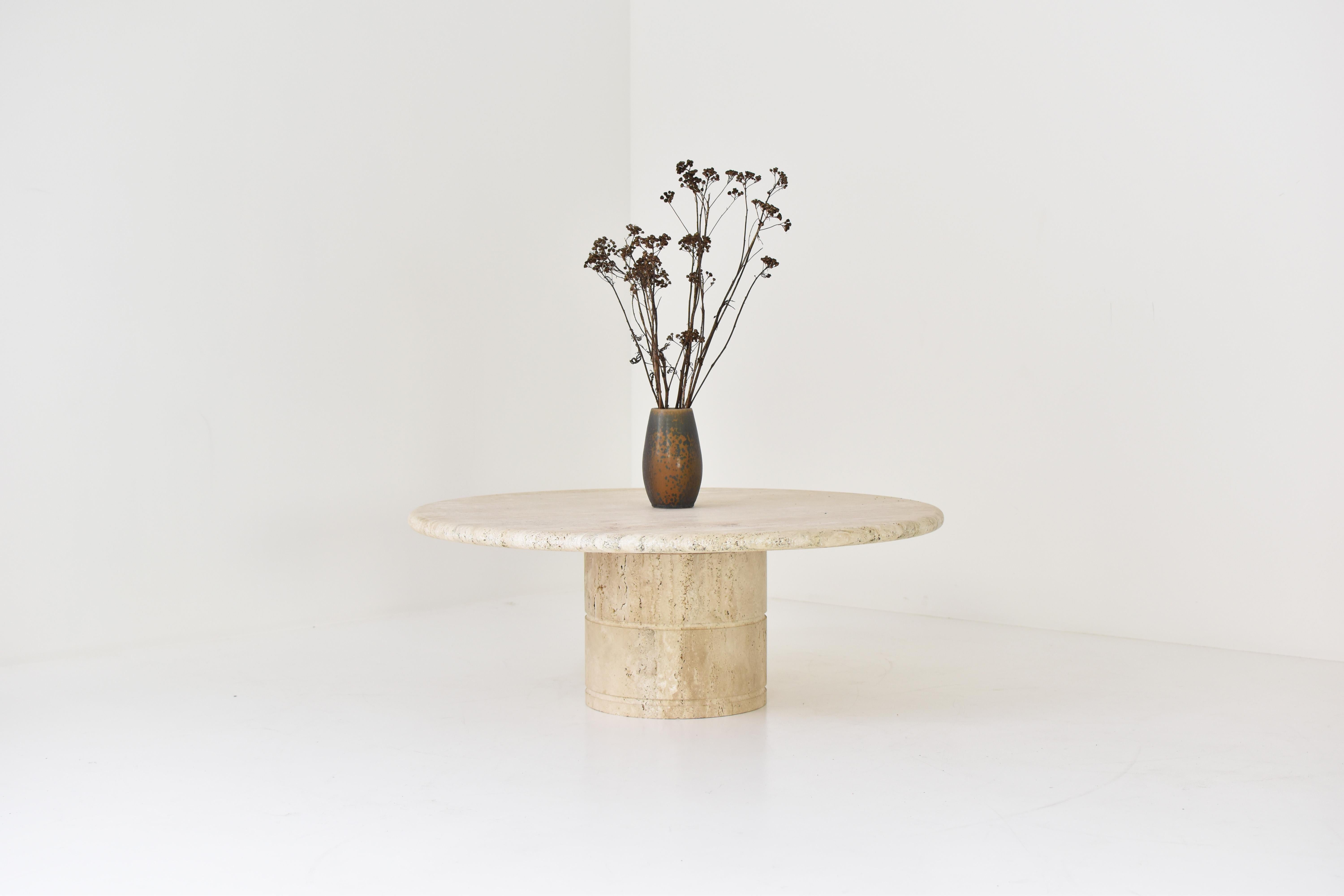 Coffee table for Up & Up, Italy 1970’s. The table is fully made out of travertine with variegated tones of beige and brown. The top rests on a unique cylinder shaped pedestal base. The table is in a beautiful and original condition.