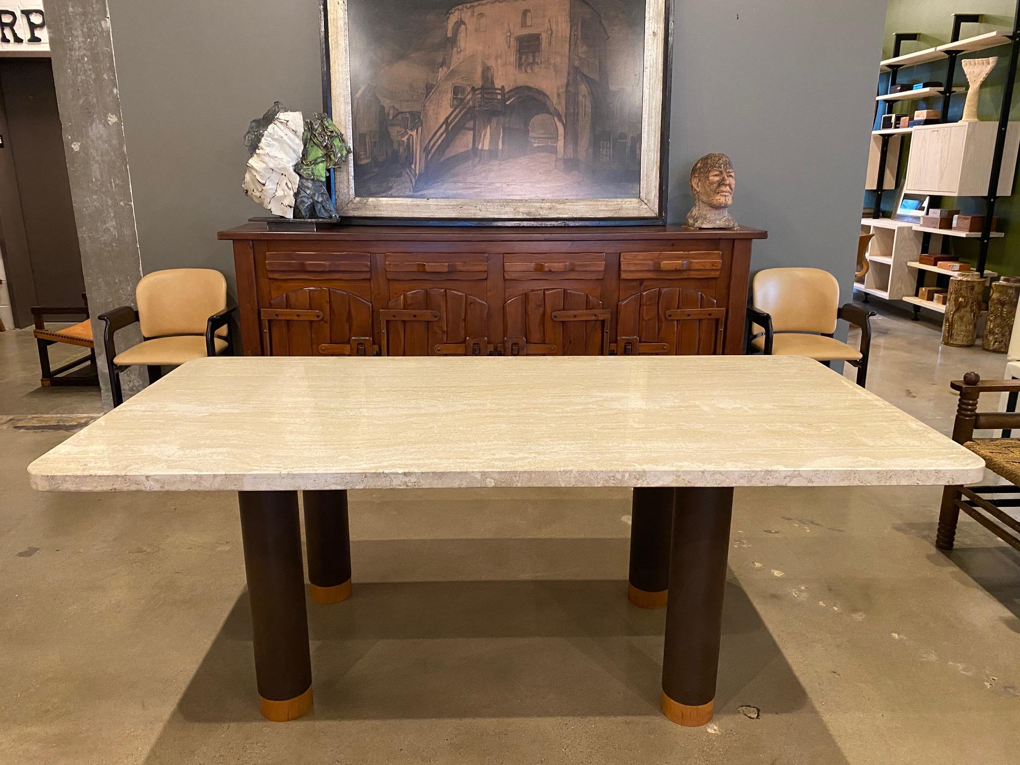 Italian travertine dining table with thick stone top. Four bronzed steel column legs are finished with solid walnut caps at the bottom. Heavy stone top with gentle radiuses at each corner. Italy, 1970's.