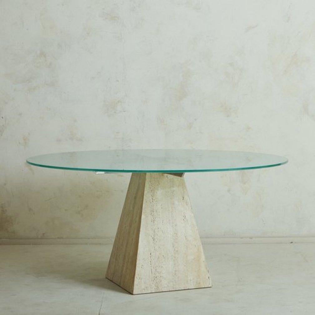 A 1960s Italian dining table featuring a triangular travertine pedestal base with elegant veining and a porous finish. It has a circular frosted glass tabletop with a bevel edge in a captivating blue hue. The top is supported by a chrome x-support
