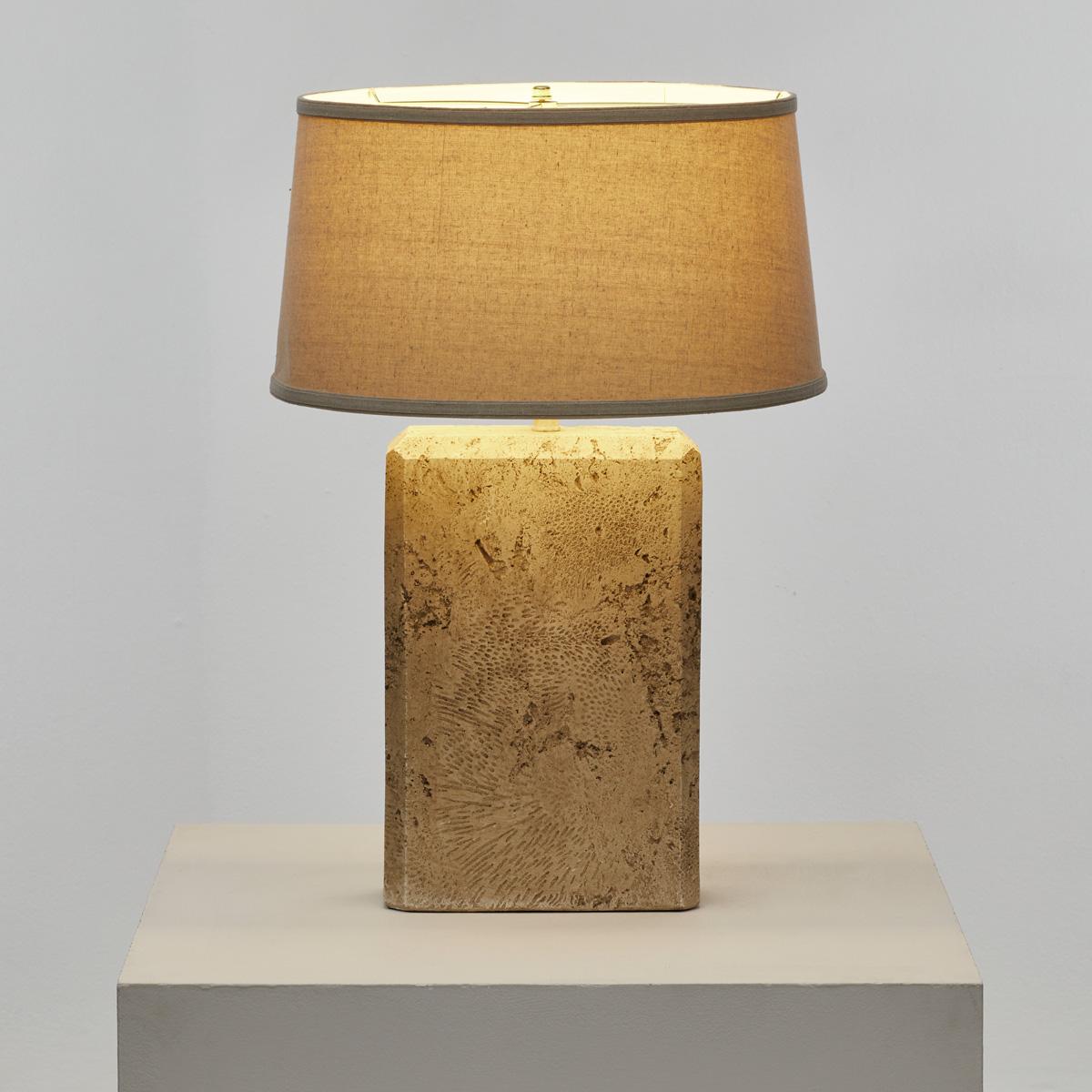 A travertine effect/composite table lamp with a shallow tapered drum shade in linen.

The base, which is not solid travertine, shows signs of wear, with some minor chips to the corners. The shade is in good used condition.