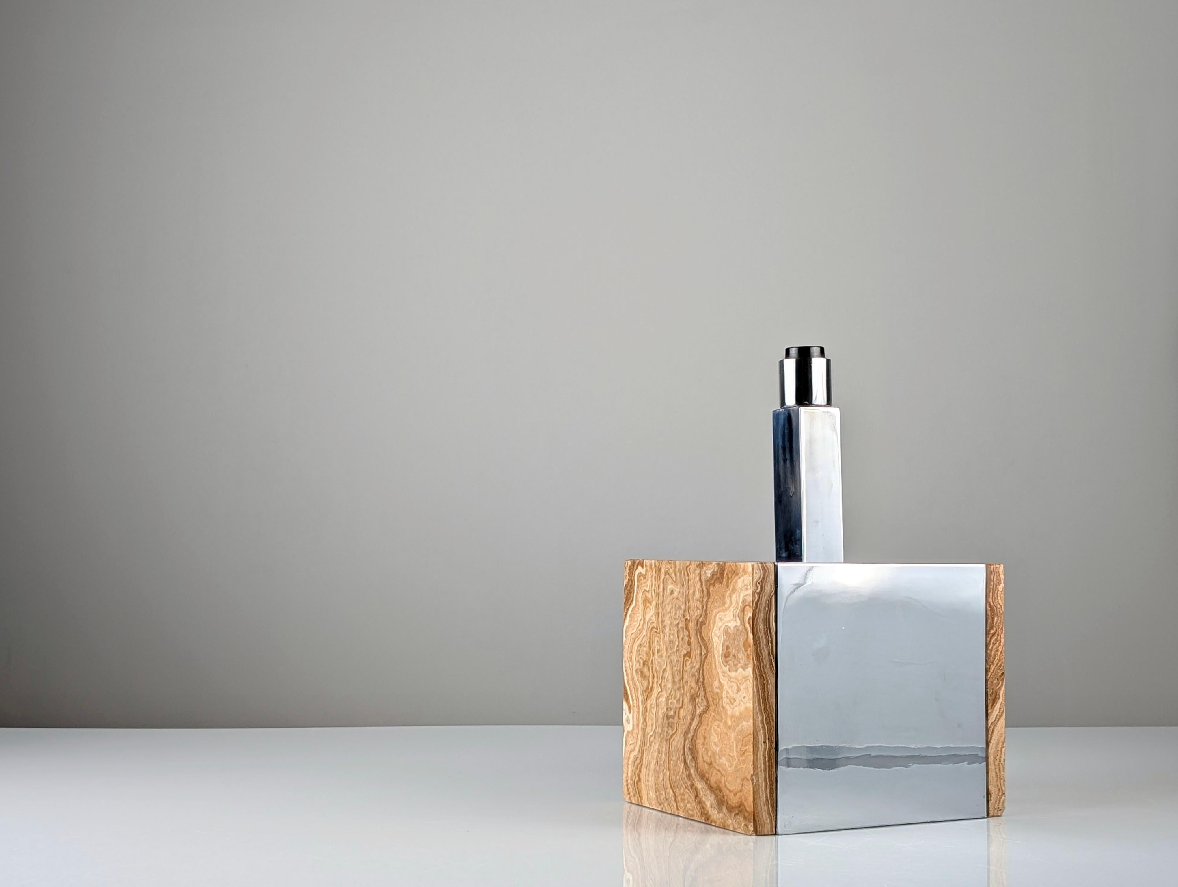 Elegant table lamp with a distinctive geometric design that combines the solidity of travertine marble with the sophistication of chrome-plated metal. This piece embodies the aesthetics of the 1960s, characterized by clean lines, high-quality