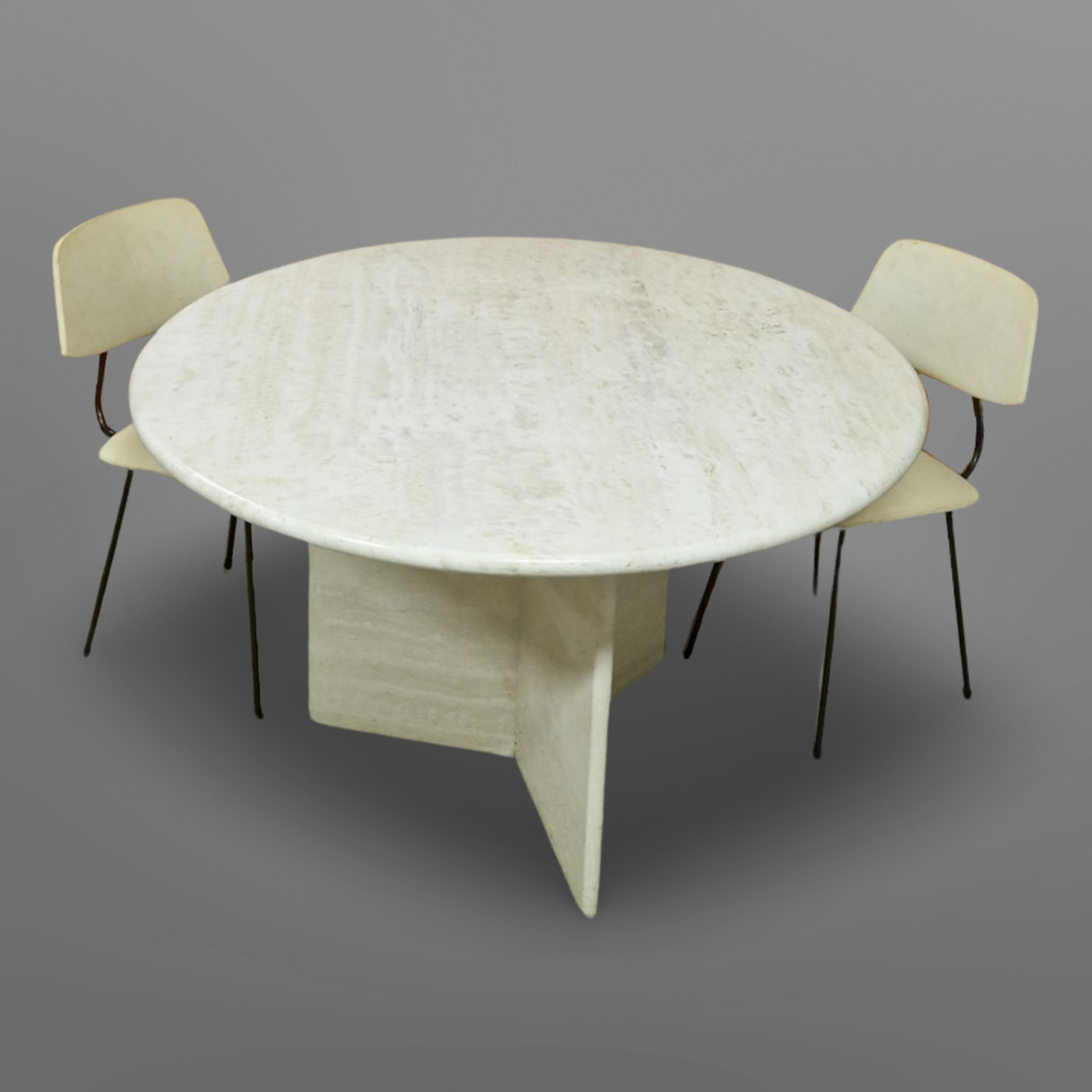 Round dining table in Hollywood regency style. Made from travertine. The 3cm thick top has a smooth surface and stand on a base made from three slabs of travertine. In the middle it has a brass point to center the top on the base. 

Travertine is a
