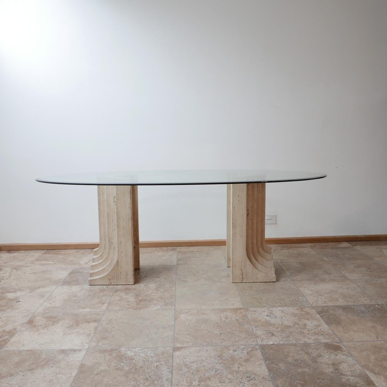 A solid travertine dual base dining table attributed to Carlo Scarpa.

Italy, circa 1970s.

Good sized beveled glass top.

Sculptural architectural form has led to Scarpa's work being used all-over the interior design world.

Some surface