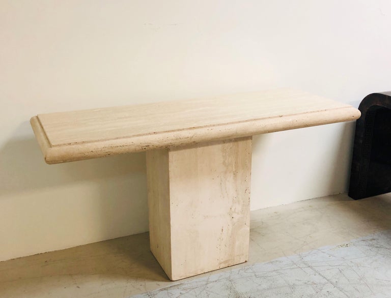 A minimalist travertine console table. The top is removable. Simple design with a rectangular base, and a slab top with a thick bullnose edge. Note the the top surface is polished and the base and bullnose perimeter are not.