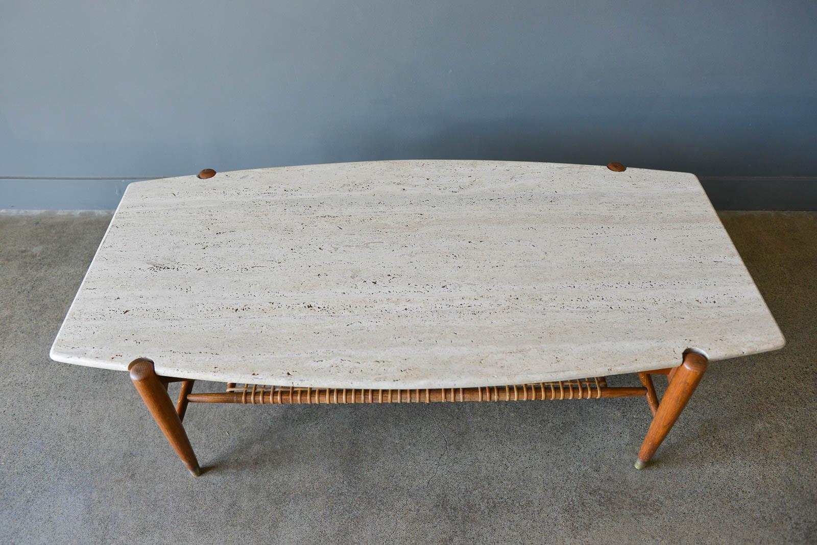 Travertine, oak and cane coffee table by Folke Ohlsson for Dux, circa 1965. Unique surfboard shape with brass tipped legs. Slight wear and some breakage to cane shelf as shown. Travertine is very good with no chips or cracks, slight wear to edges.
