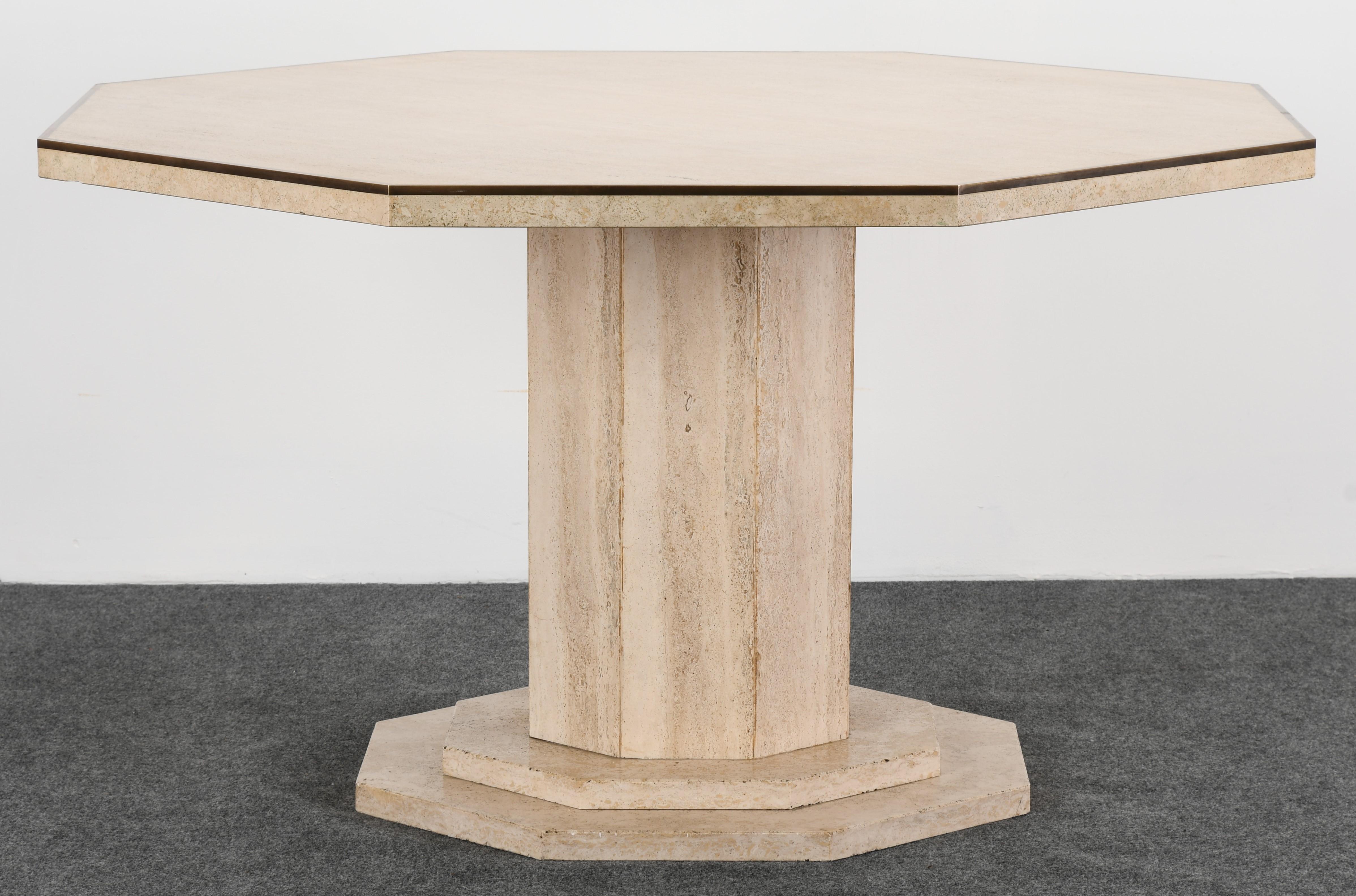 An impressive Roche Bobois style travertine octagonal dining table with brass trim on a stacked travertine pedestal. The table is in good condition with age appropriate wear. Would make a great center table for a hallway or entryway, as well as a