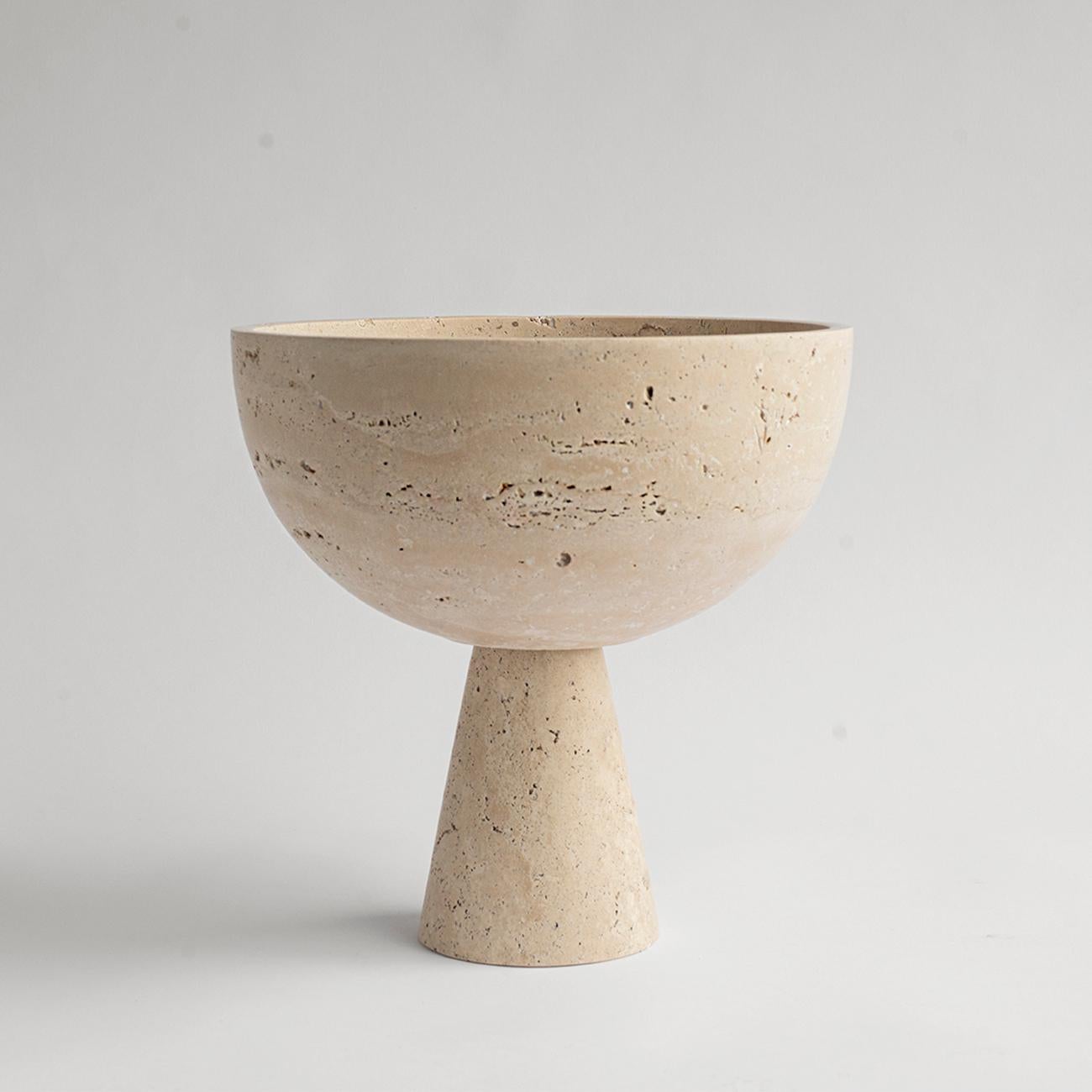 A substantial travertine bowl with unique structure rests atop a pedestal for a grand presentation of fruits and vegetables. 

Due to the nature of the material, each piece may vary slightly in appearance. We encourage embracing the variations