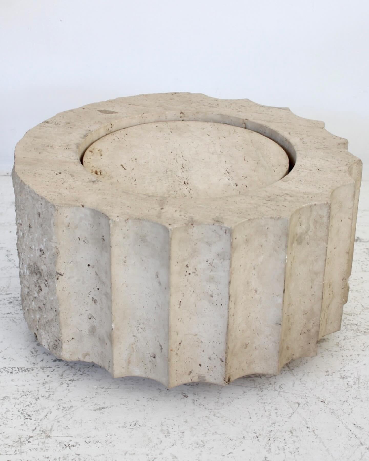 Hand carved Travertine marble fluted column side table. Origin France. The table is hand carved all around and then features a side that is purposely rough carved to appear as if the carver is in process. Almost a surrealist object. A piece unique.
