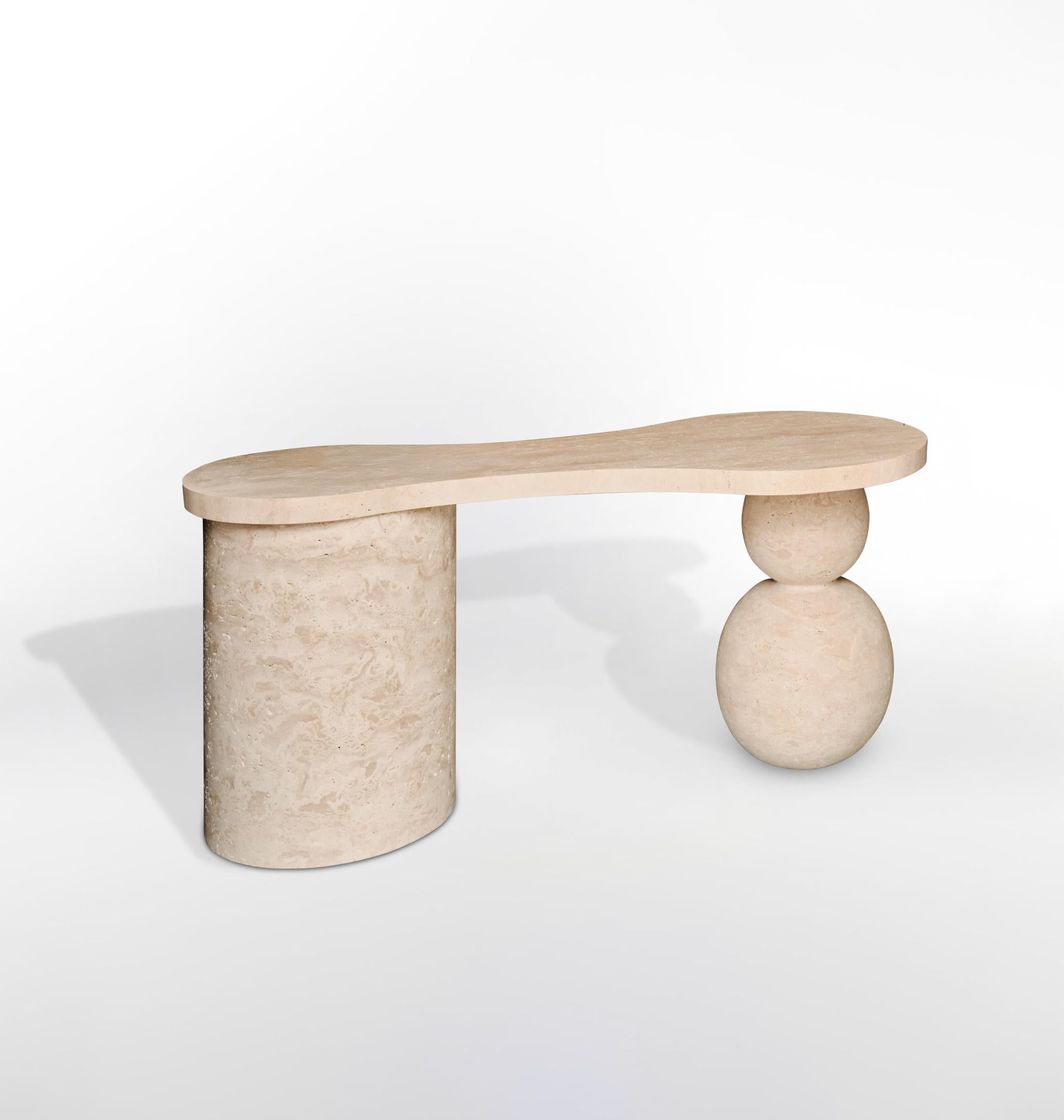 This minimalist desk is crafted entirely from natural travertine, designed to make a bold yet refined statement in any space. The organic, flowing shape of the desktop is balanced by its distinctive sculptural base—two stacked sphere-shaped legs