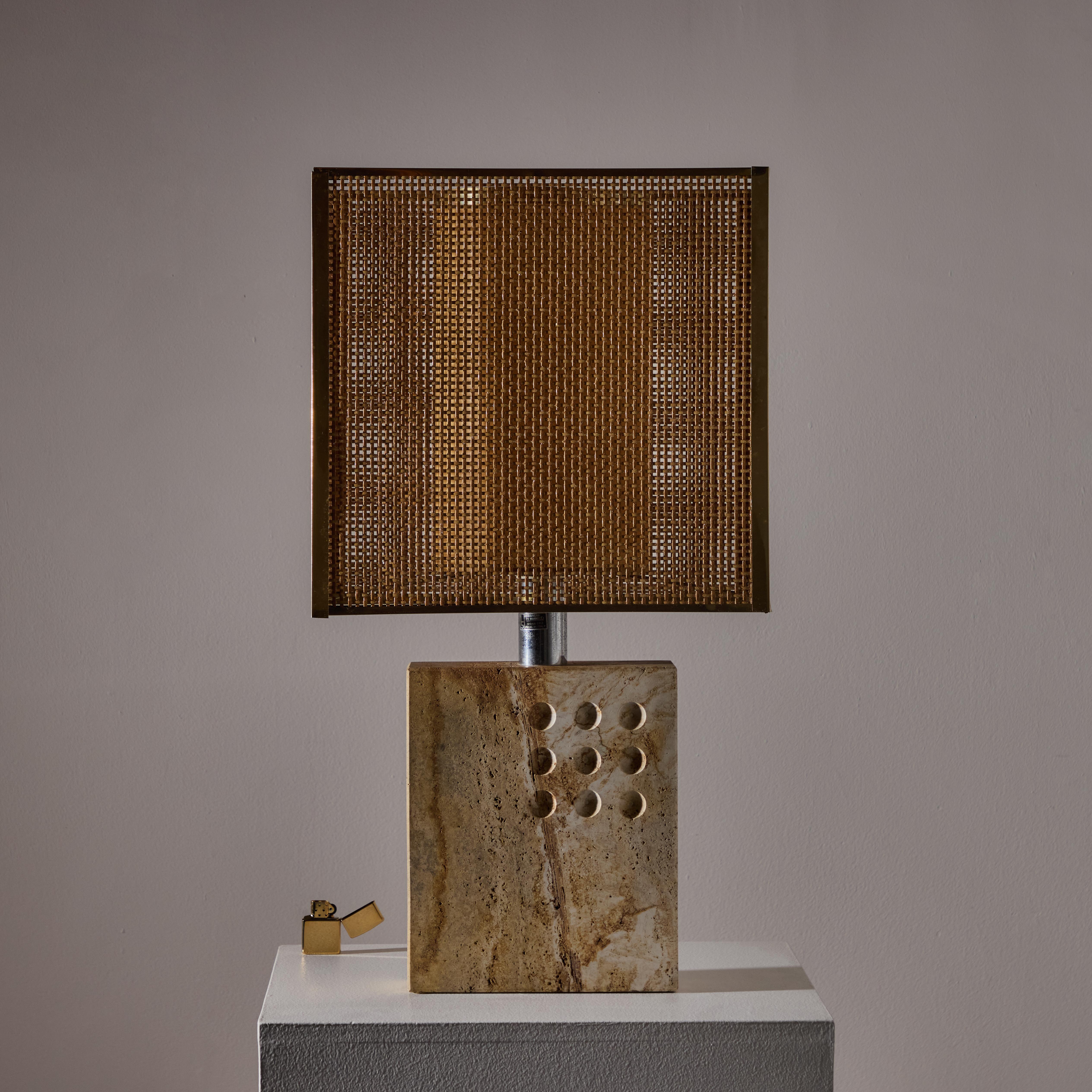 Large rectangular travertine base receives natural coarseness and decorative impressions. The shade features a two part diffuser in way of a cylindrical paper inner diffuser coupled with an exterior wicker rectangle shade. The light holds a single