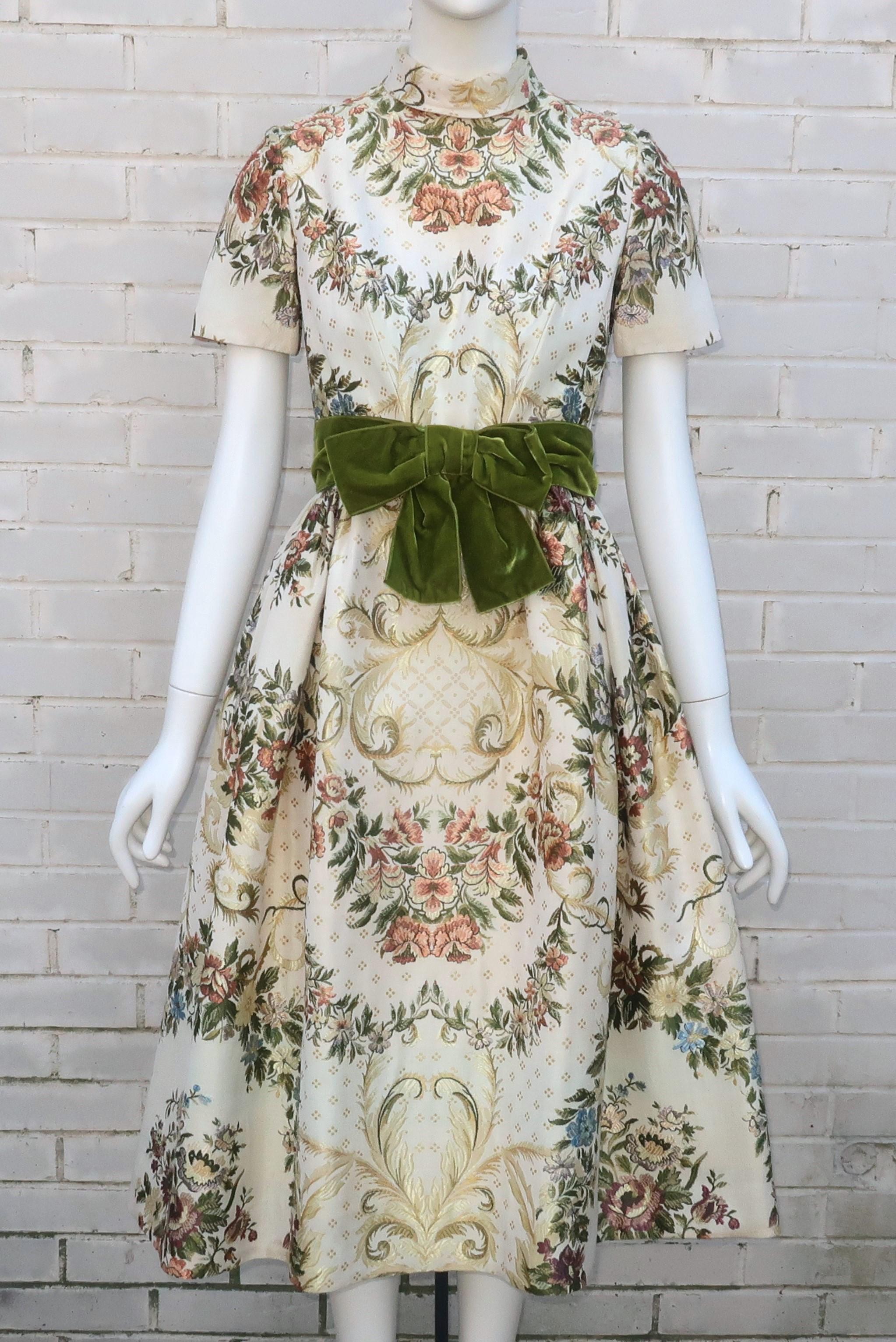 1950’s Travilla ornate brocade dress with a built-in velvet bow belt.  The rolled collar dress zips and hooks at the back with hooks and snaps at the belt.  The gorgeous fabric is an upholstery weight with details reminiscent of 18th Century French