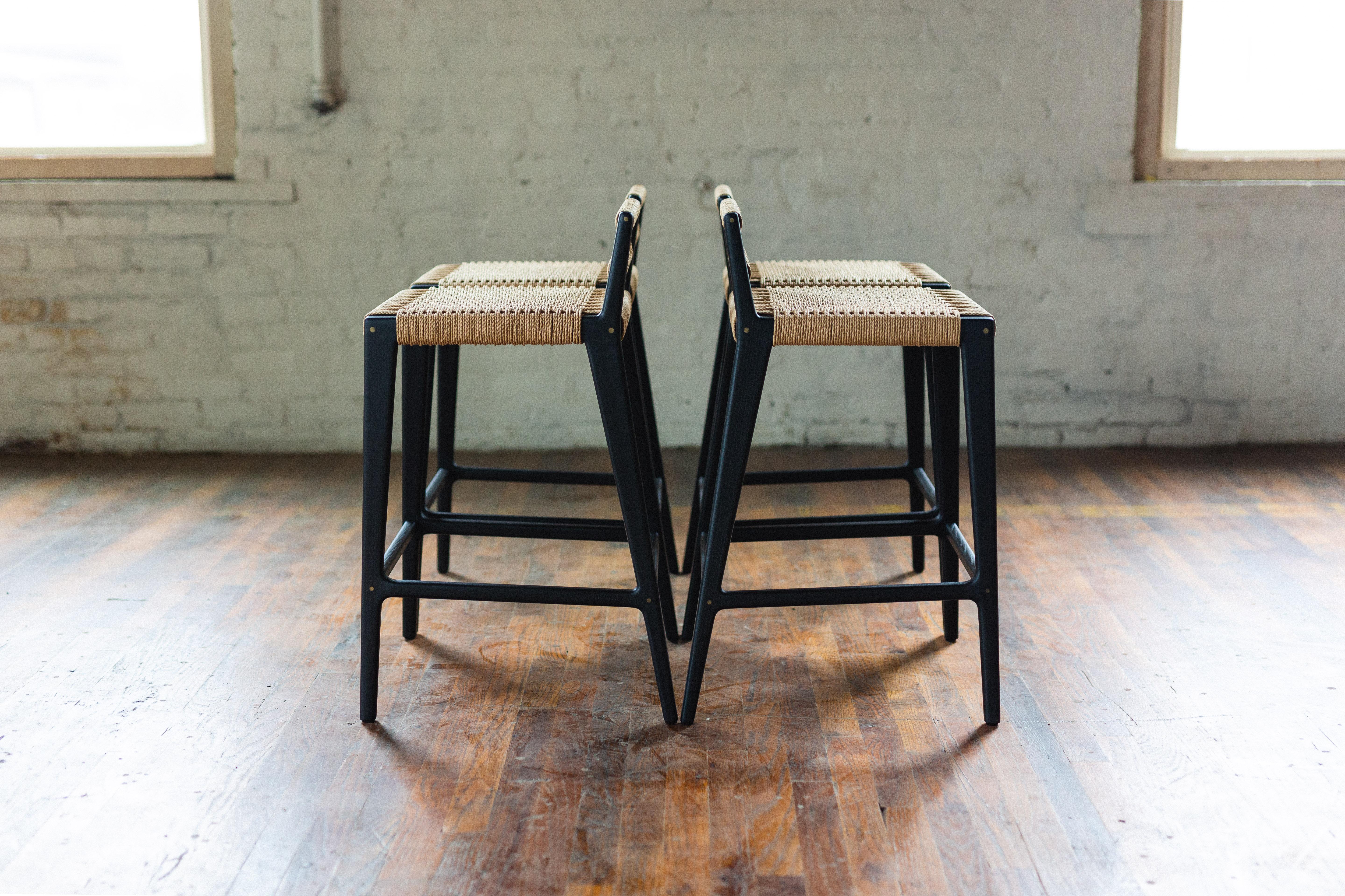 Clean, modern angles complimented by the warm texture of the Danish cord. The Travis stool can be made counter-height or bar-height with different back heights. Shown here in low back with the optional brass leg rest inlay.

All wood construction