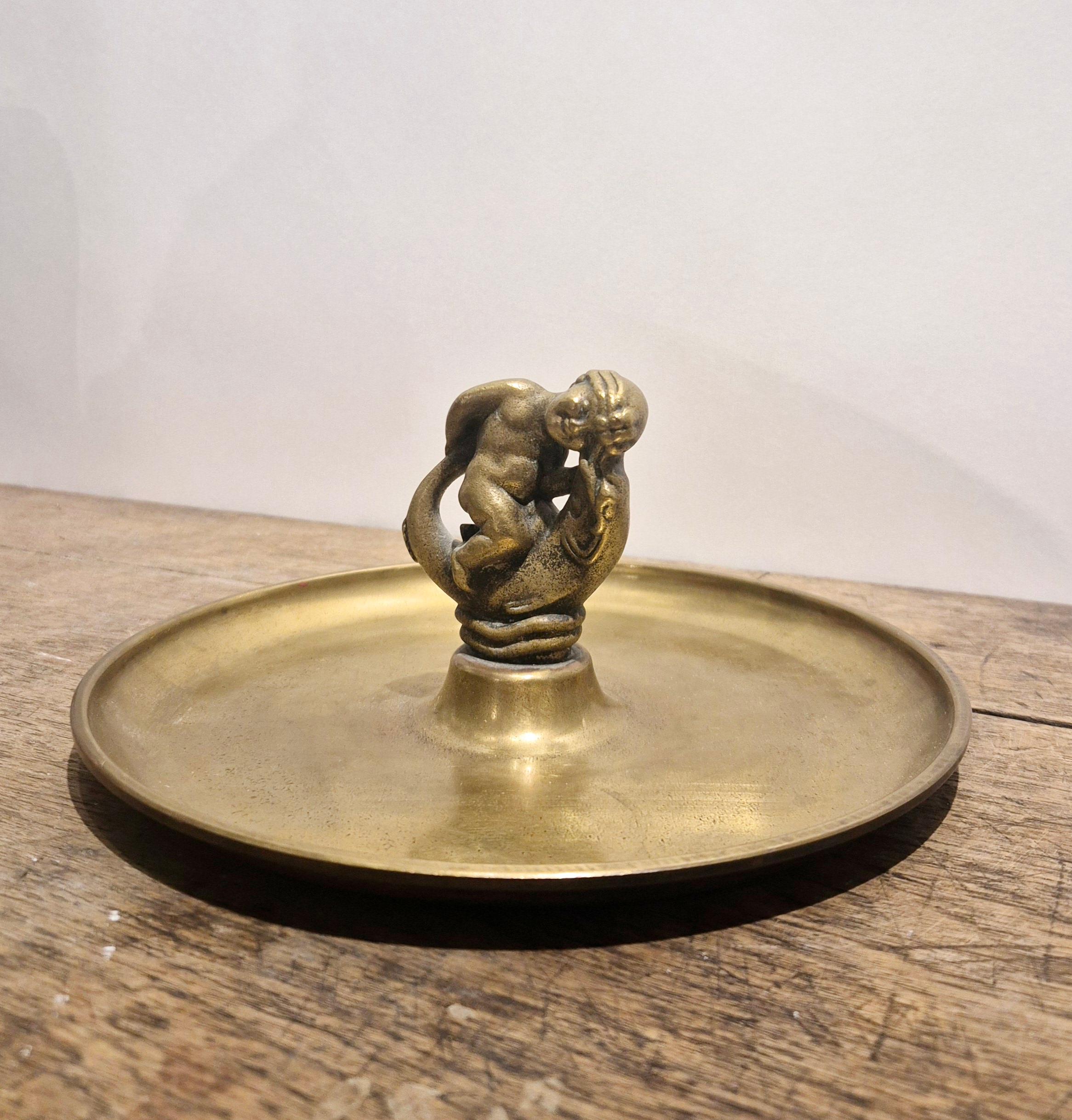 A decorative tray / vide-poche with sculpture depicting putto / child seated on and playing with fish. 

In solid bronze, with hallmarks: Ystad Brons, Sweden, Bronze. 

