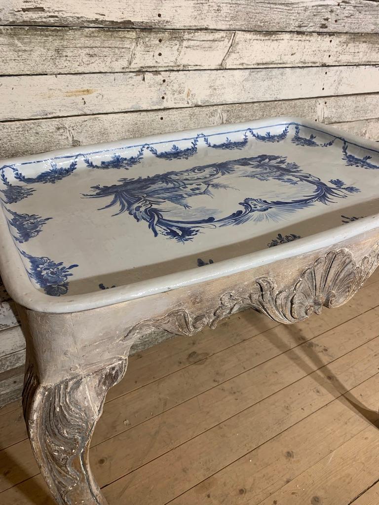 A unique tray table from Rörstrand made in faience. The top is in a blue colour, hand painted with a french, floral inspired motive (common for Rörstrand porcelain during that period). On the back of the tray there is a signature saying, 