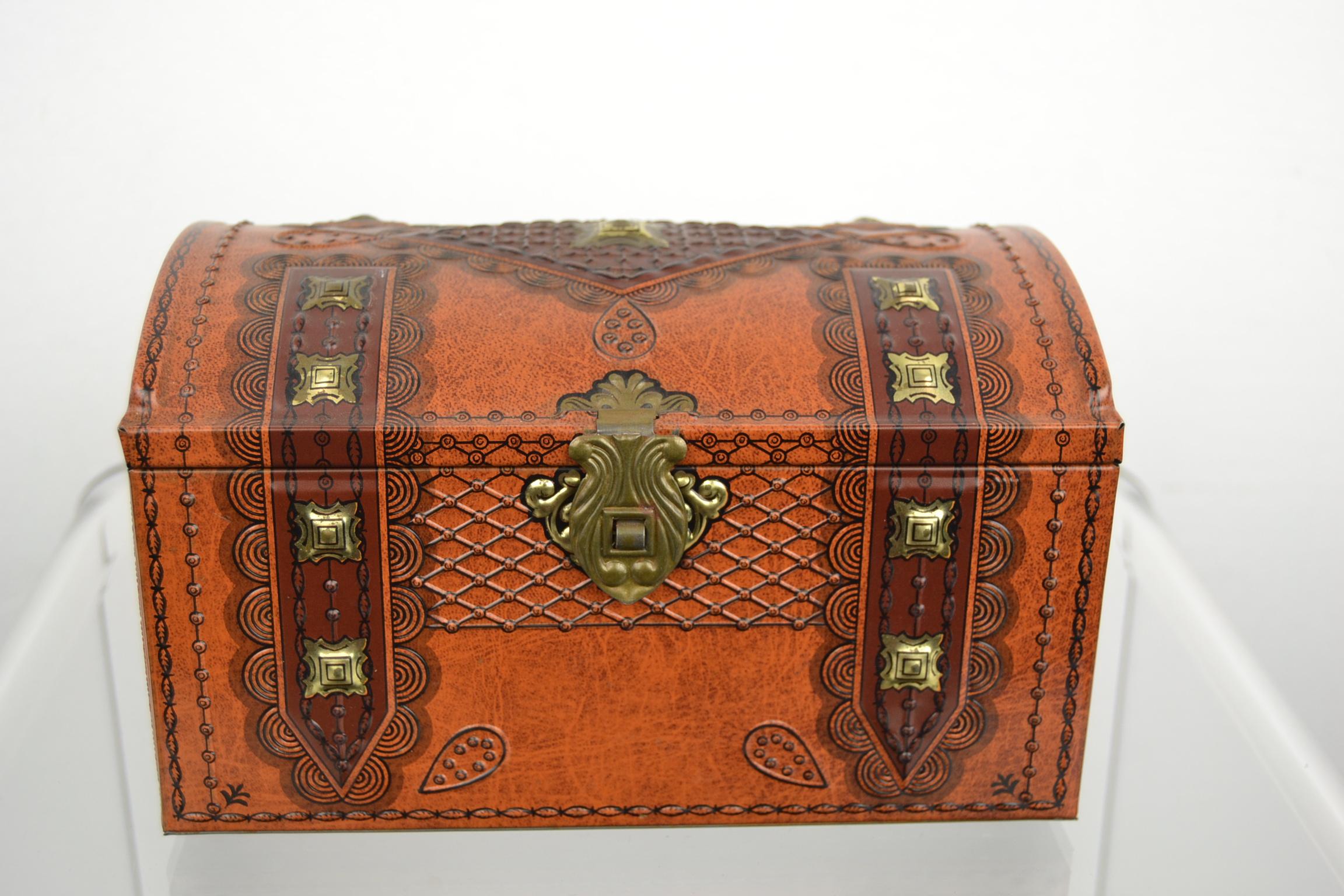 Treasury tin or coffer tin with beautiful lion heads on.
This vintage tin box has a beautiful shape, a rounded lid, embossed lion heads left and right,
a lock, embossed gold colored details and beautiful black details like circles and