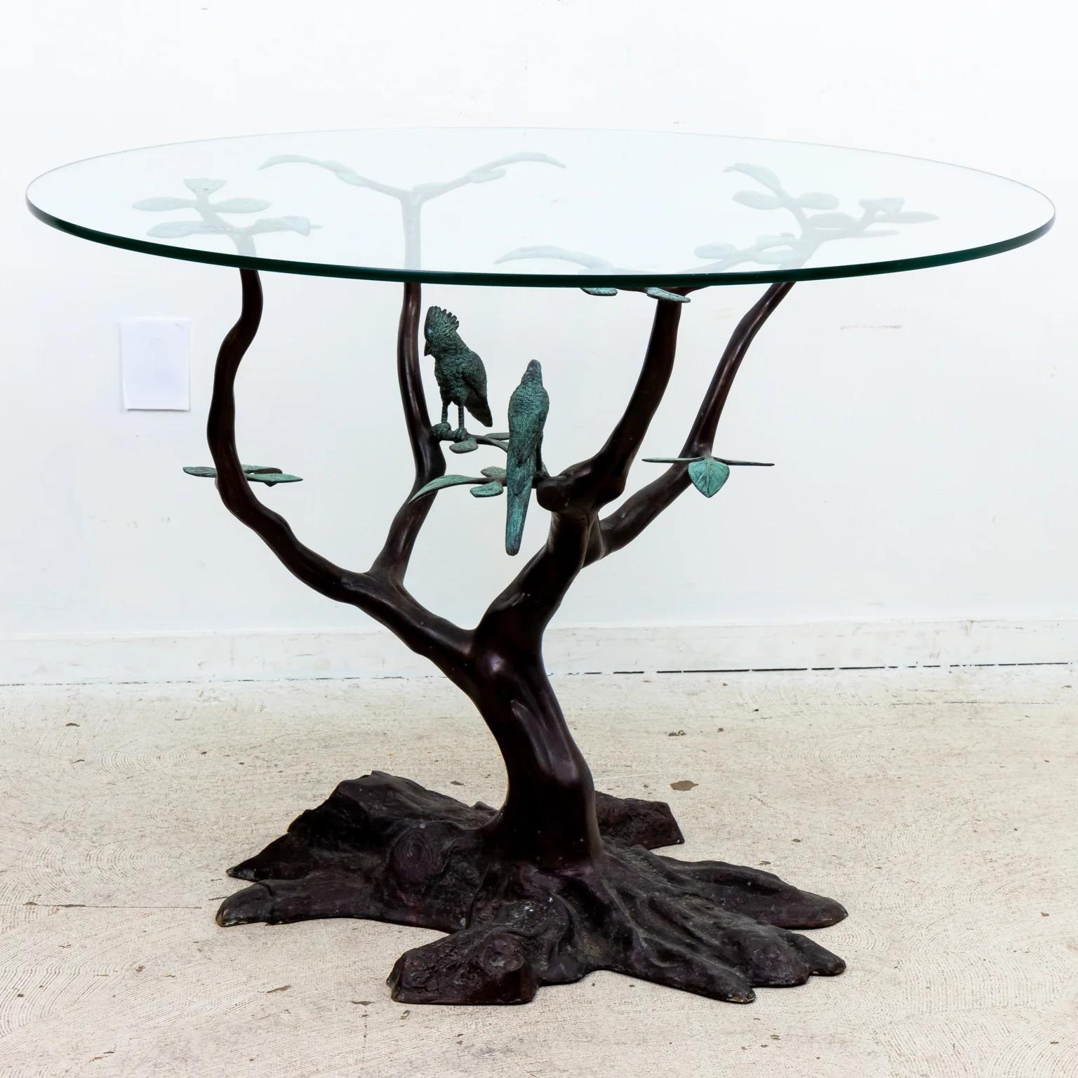 A patinated brass tree form table with two molded tropical birds resting on its branches. The round glass top supported a by sparse series of leaves. Made by hand with La Barge paper label on the underside of the base. The overall design reminiscent