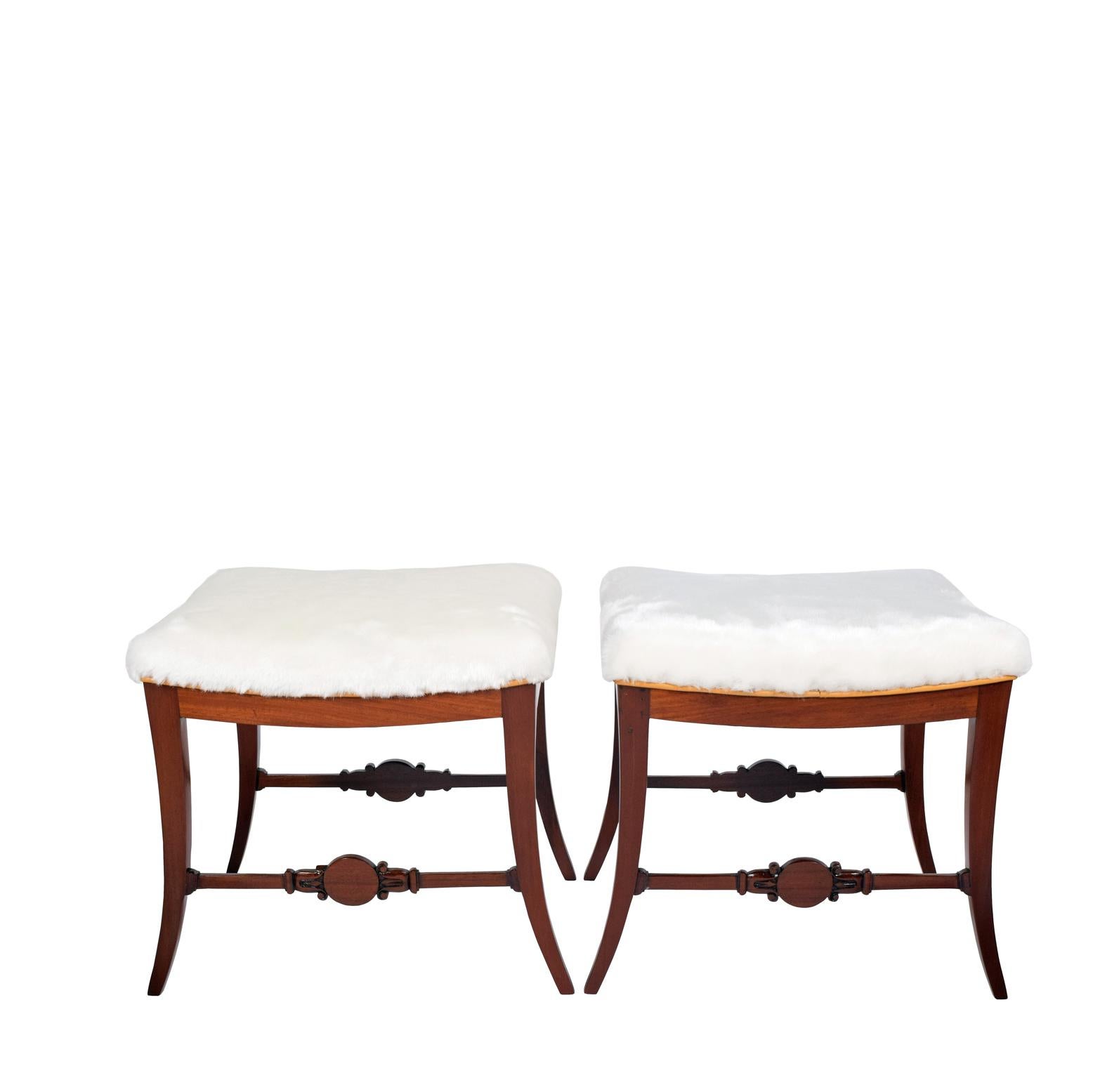 Sold in pairs

 the antique wooden stools upholstered in faux fur with leather raised on sabre legs joined by a cross-stretcher with a carved medallion.Same with old repairs and minor crack to the wood.