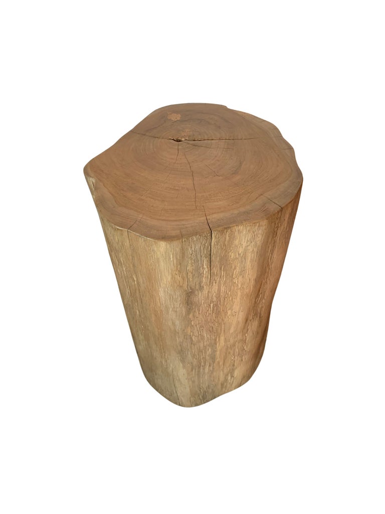A wonderfully organic round side table. Its neutral pigment and subtle wood texture makes it perfect for any space. This table was crafted from a solid trunk of teak wood. The table top was meticulously sanded down and finished with a clear coat