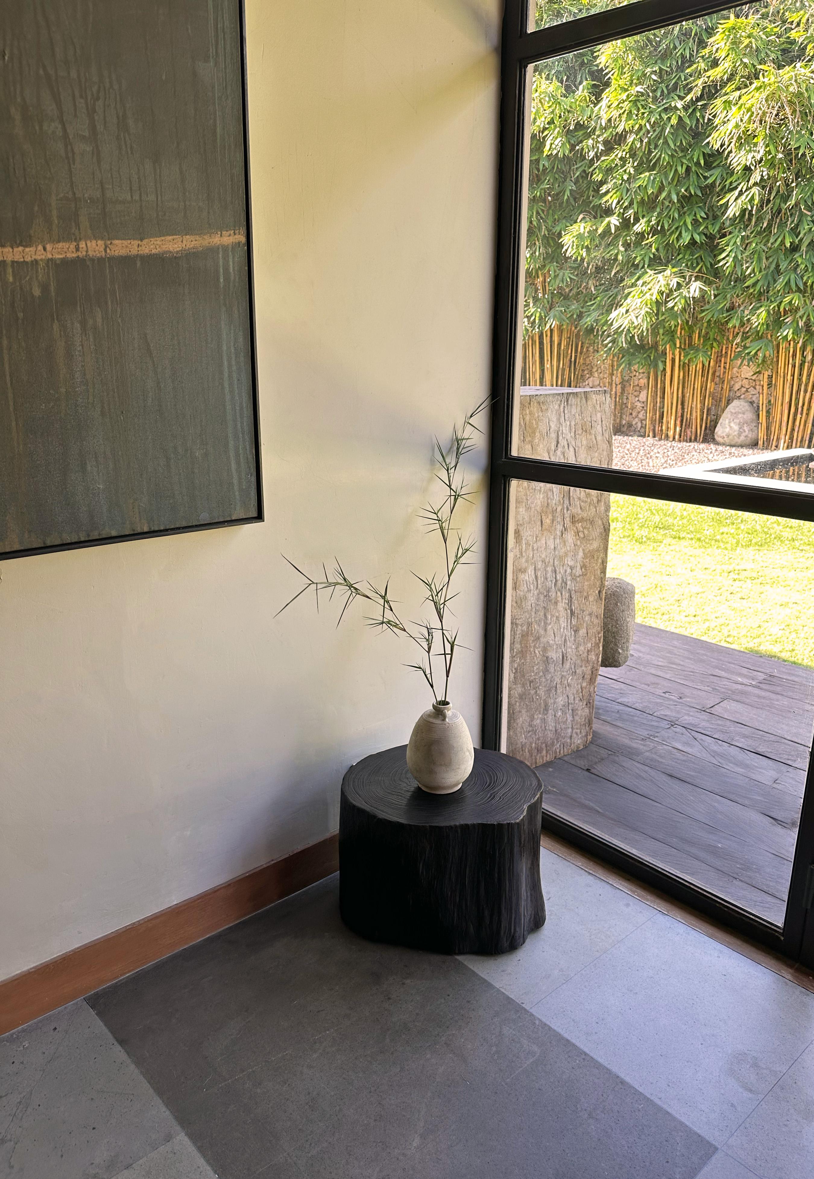 Une table d'appoint ronde merveilleusement organique. Son pigment neutre et sa texture boisée subtile s'intègrent parfaitement à tous les espaces. Cette table a été fabriquée à partir d'un tronc solide en bois de teck. Le mélange des teintes et des