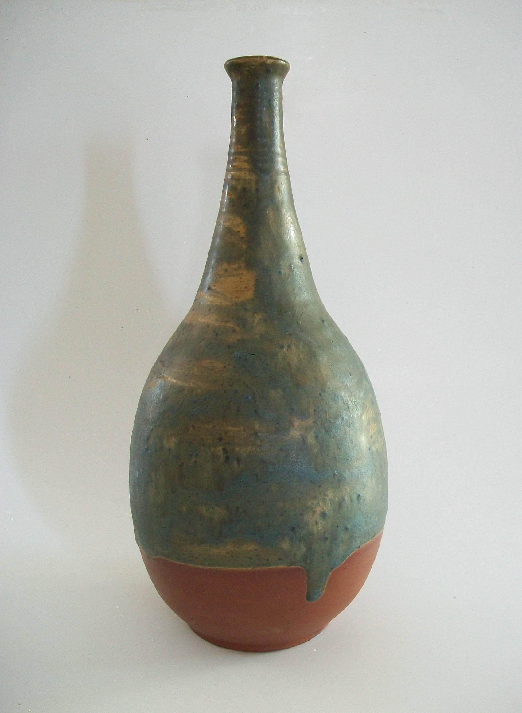 TREIMANE ART POTTERY (Active - 1949 to the early 1990's) - Mid Century studio pottery bottle vase - featuring a wheel thrown terracotta body with a hand painted dripping sand infused textured matte gray glaze over a caramel color glaze to the top