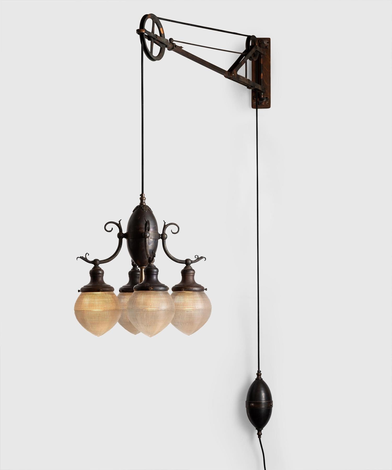 Trenaman swing arm pulley lamp, America circa 1912.

Rare iron dentist lamp with four matching acorn Holophane globes, wooden backplate, and ornate details. Manufactured by Trenaman Dental MFG. CO. in New York.