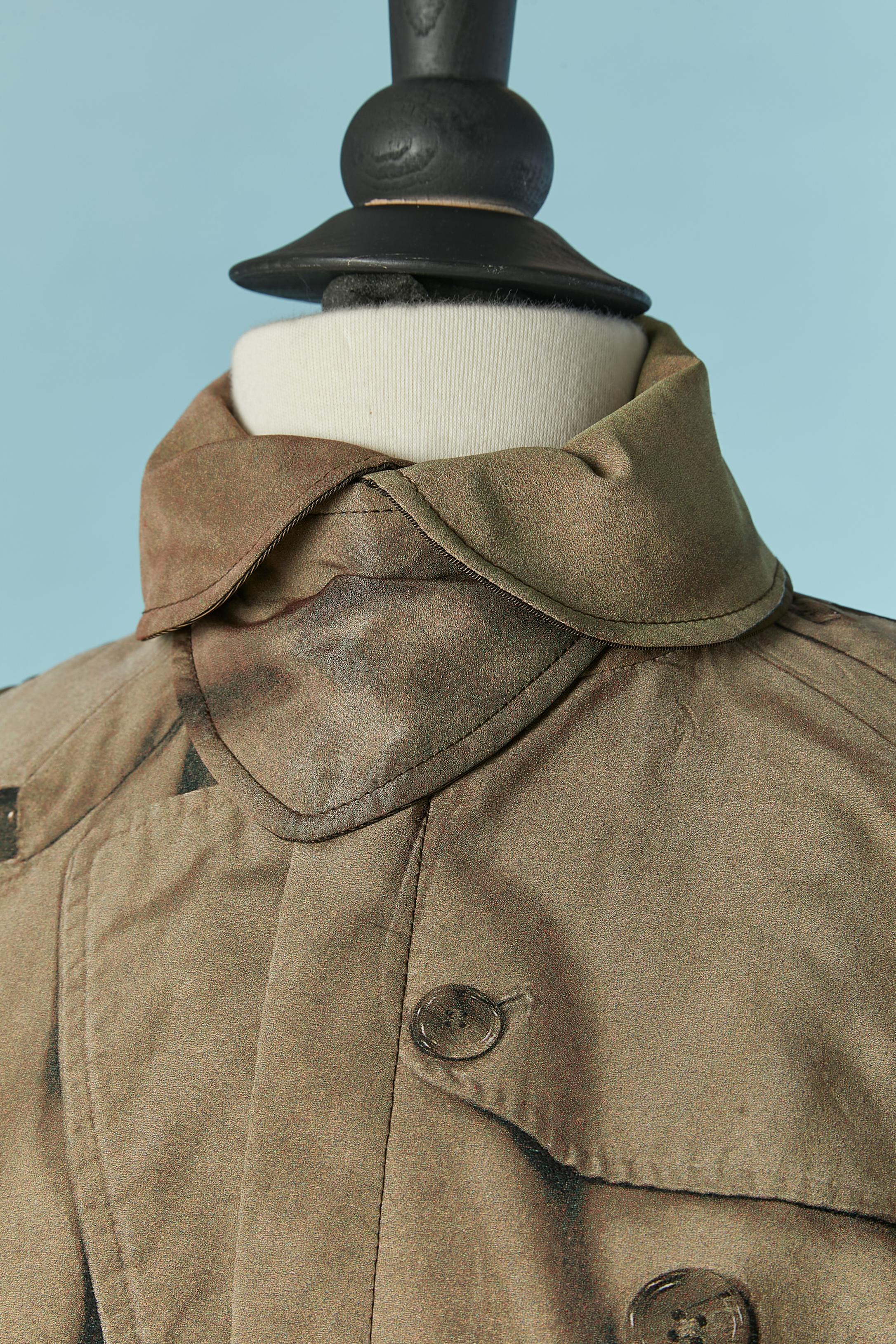 Trench con stampa Trompe l'Oeil. Composizione del tessuto principale: 100% poliestere. Composizione della fodera: 70% acetato, 30% rayon. 
Chiusura con zip al centro della fronte. Maniche raglan. Tasca su entrambi i lati. Cintura sulle maniche.