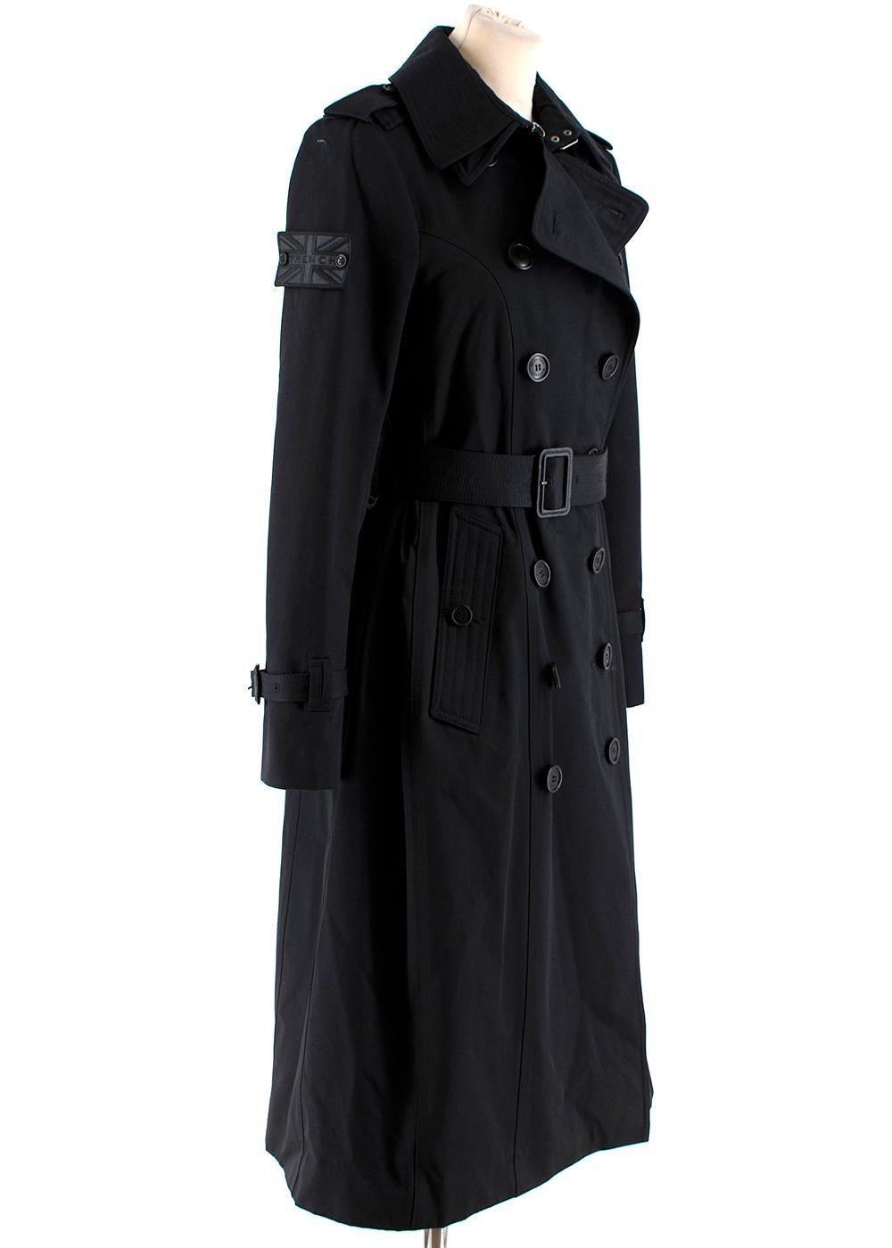 Trench London Black Sloane Trench Coat

- Black trench coat 
- Double breasted 
- Double collar 
- Structured gabardine cloth 
- Leather buckles
- Epaulettes, hook and eye collar closure
- Gun flap, belted cuffs, d-ring waistband 
- Side arm patch