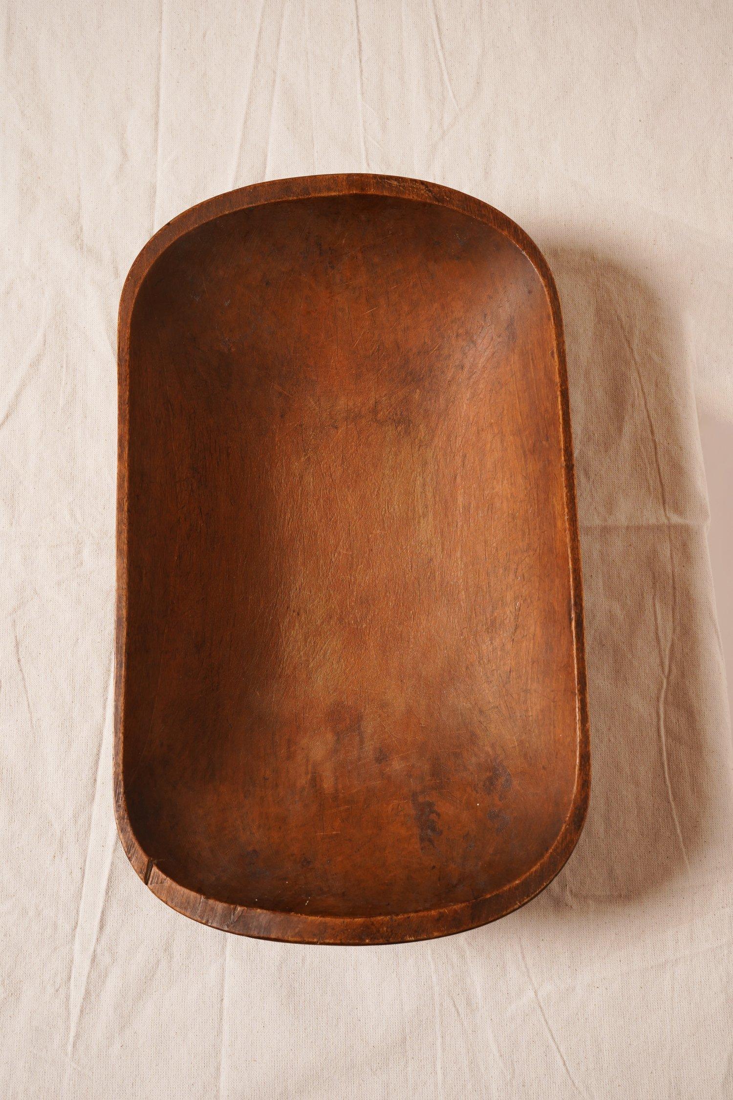 This trencher rectangular wooden dough bowl was traditionally used to prepare dough in the 19th century. This bowl can be used for storage or displayed as is.