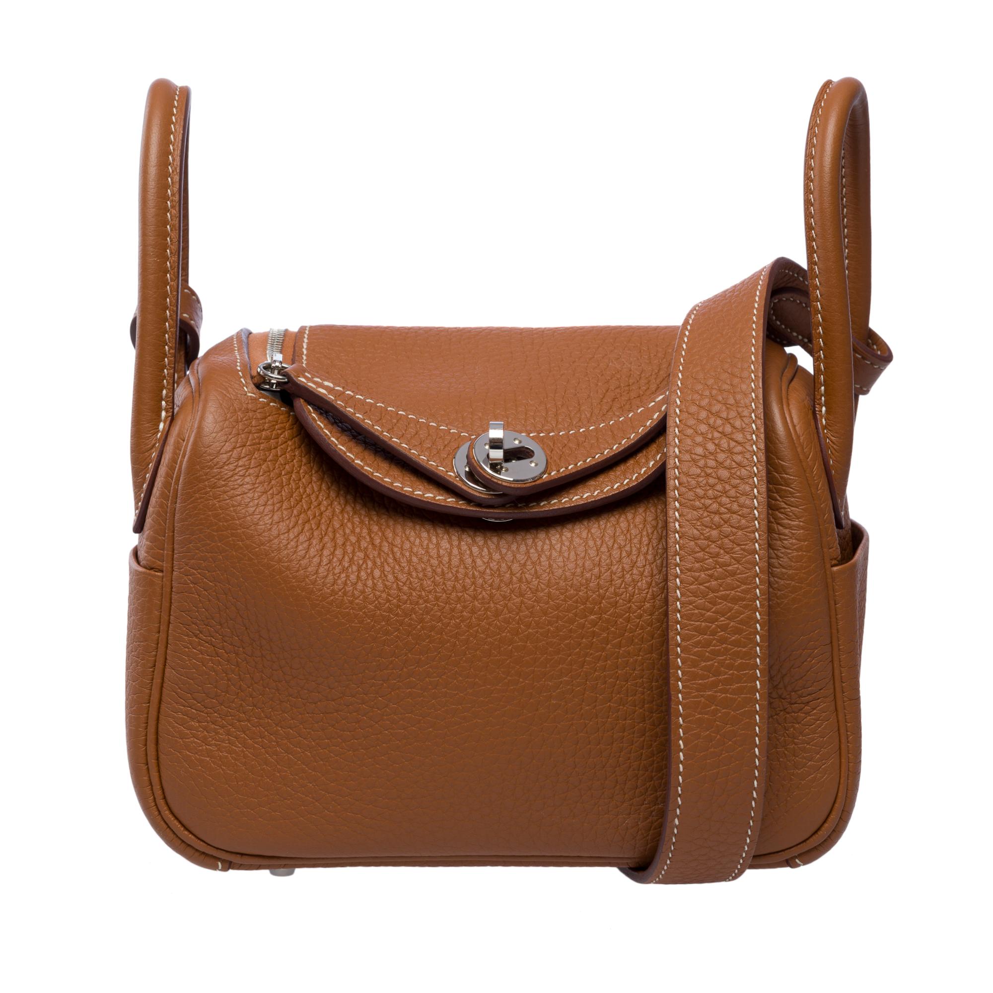 Mini borsa Hermès Lindy di tendenza in pelle togo oro con cuciture bianche, finiture in metallo palladio, doppio manico in pelle togo oro, un semplice manico in pelle togo oro che permette di portarla a mano, a spalla o crossbody.

Chiusura con zip
