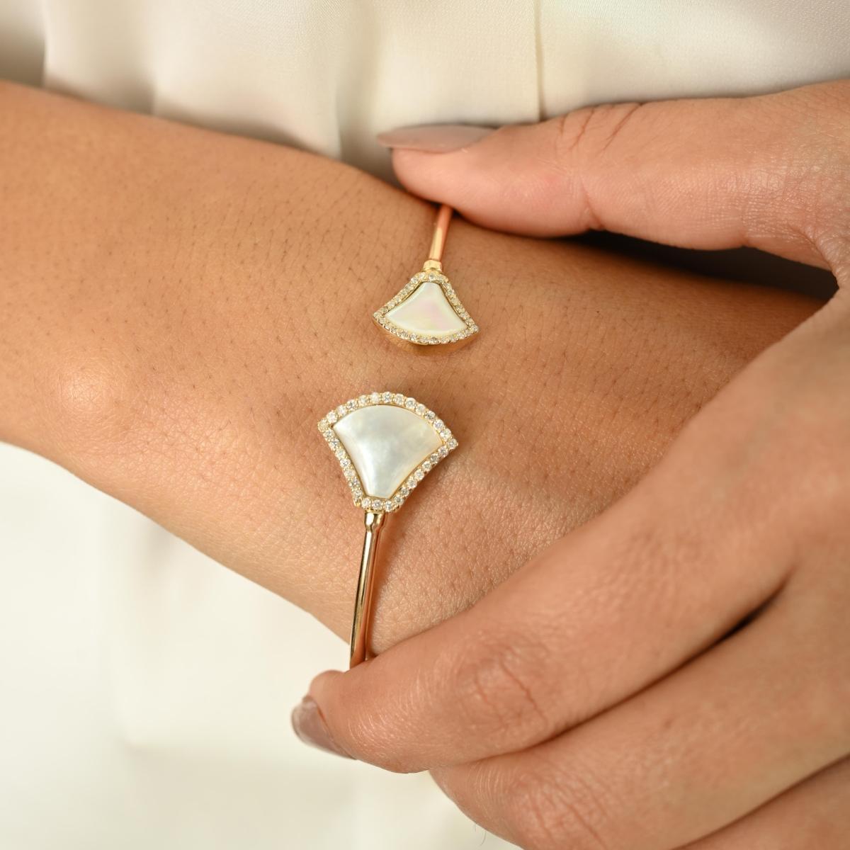 Élevez votre élégance quotidienne avec ce gracieux bracelet en or jaune 14k, qui présente un design ouvert moderne orné de motifs lumineux en forme d'éventail. Chaque extrémité est sertie d'incrustations lisses et nacrées délicatement encadrées par