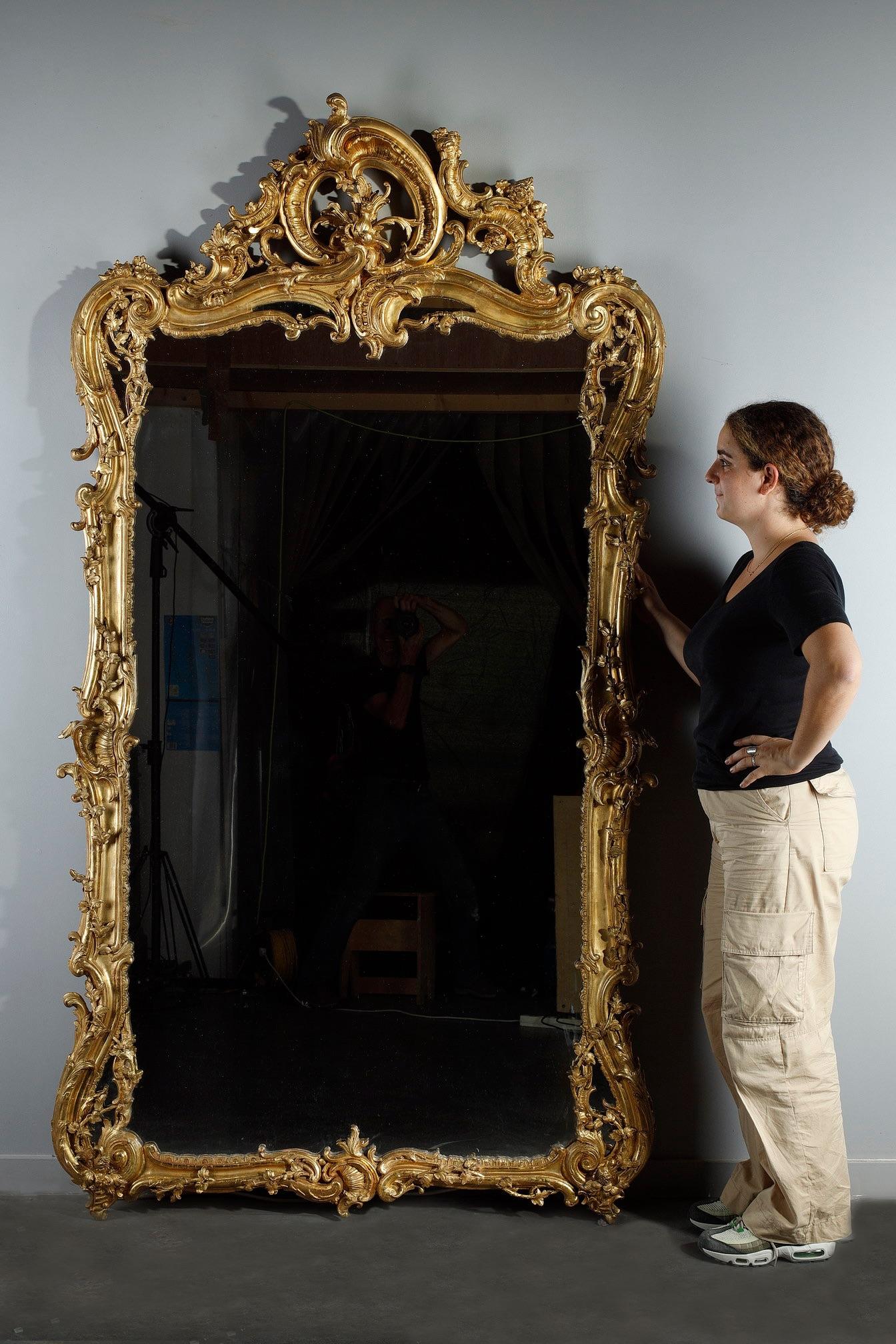 Large giltwood Rocaille mirror in Louis XV style, decorated with plant motifs of acanthus leaves, climbing ivy, flowers and shells. The large scrolls at the corners allow for mirror inlays making the composition of this rococo mirror very moving.
