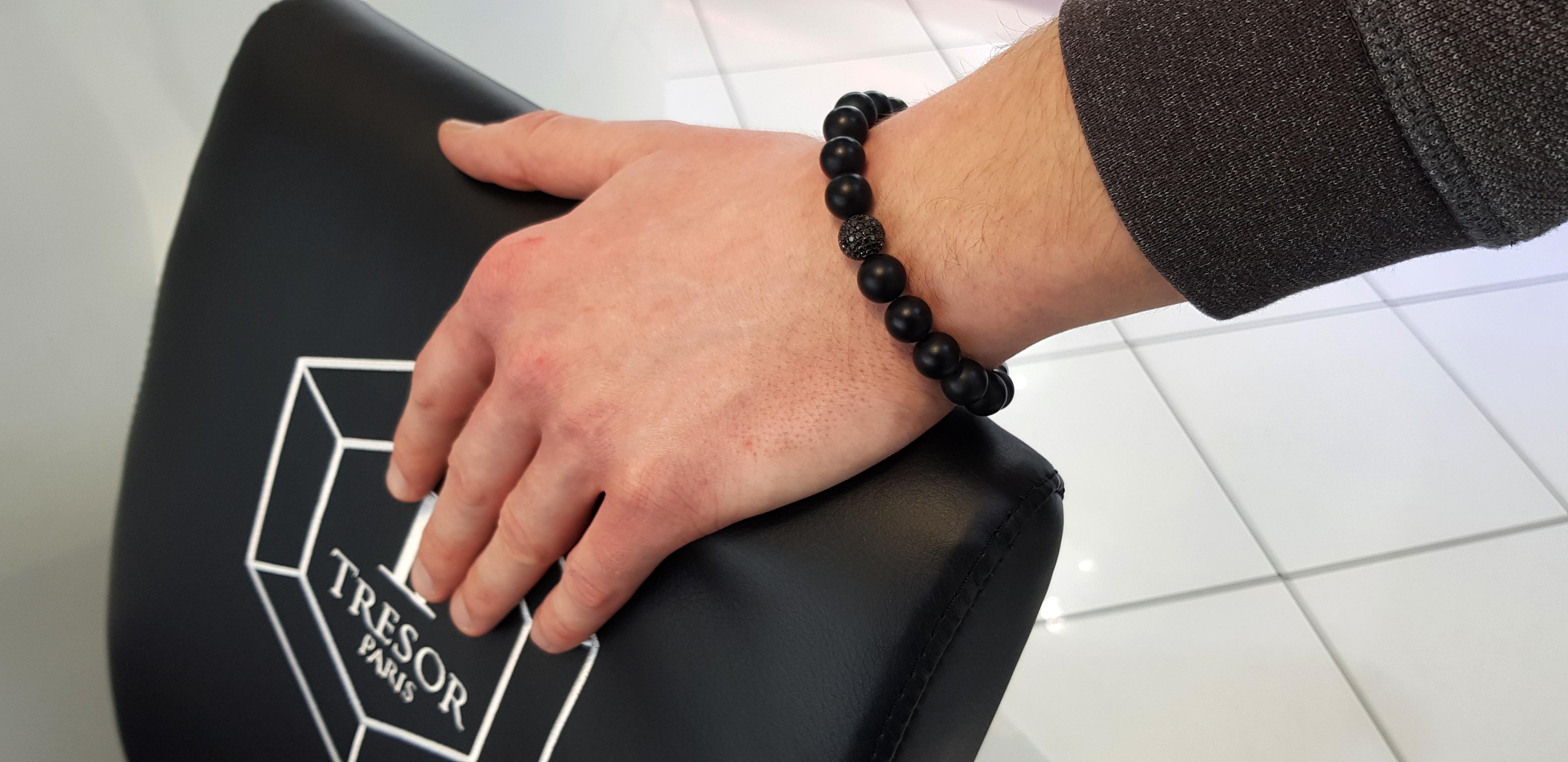 L'original bracelet Tresor Paris de la collection Jubilée est orné d'une perle de diamants ronds noirs sertis en pavé de 1,80 carat, en or blanc 18 carats. Le bracelet comporte 3 perles en acier inoxydable et 17 perles en agate satinée noire matte.