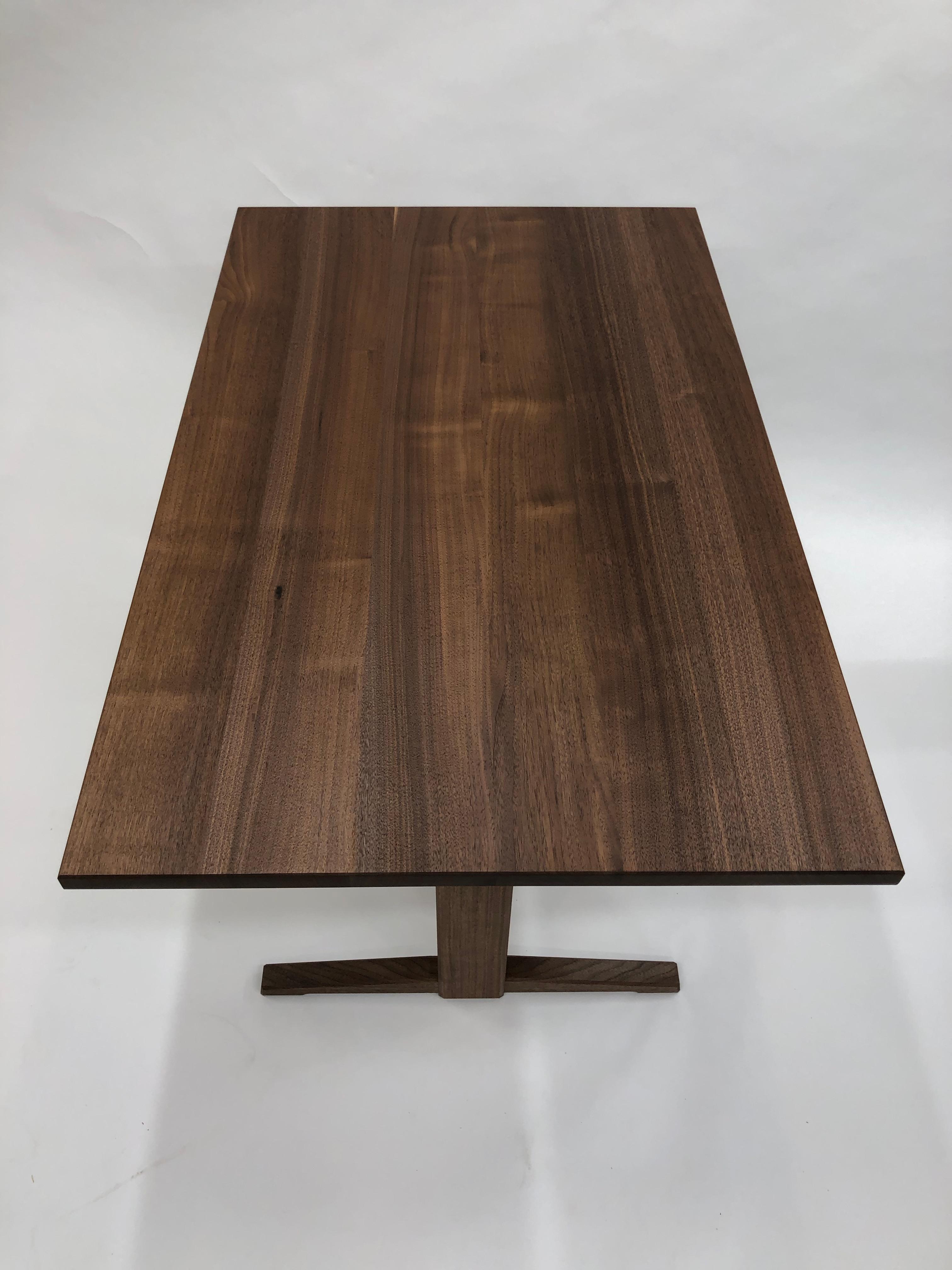 Dining table in quarter sawn walnut featuring a trestle base, carefully constructed utilizing interlocking joinery and without metal hardware or screws. The construction of this tables follows the technique of Japanese timber joinery to create a